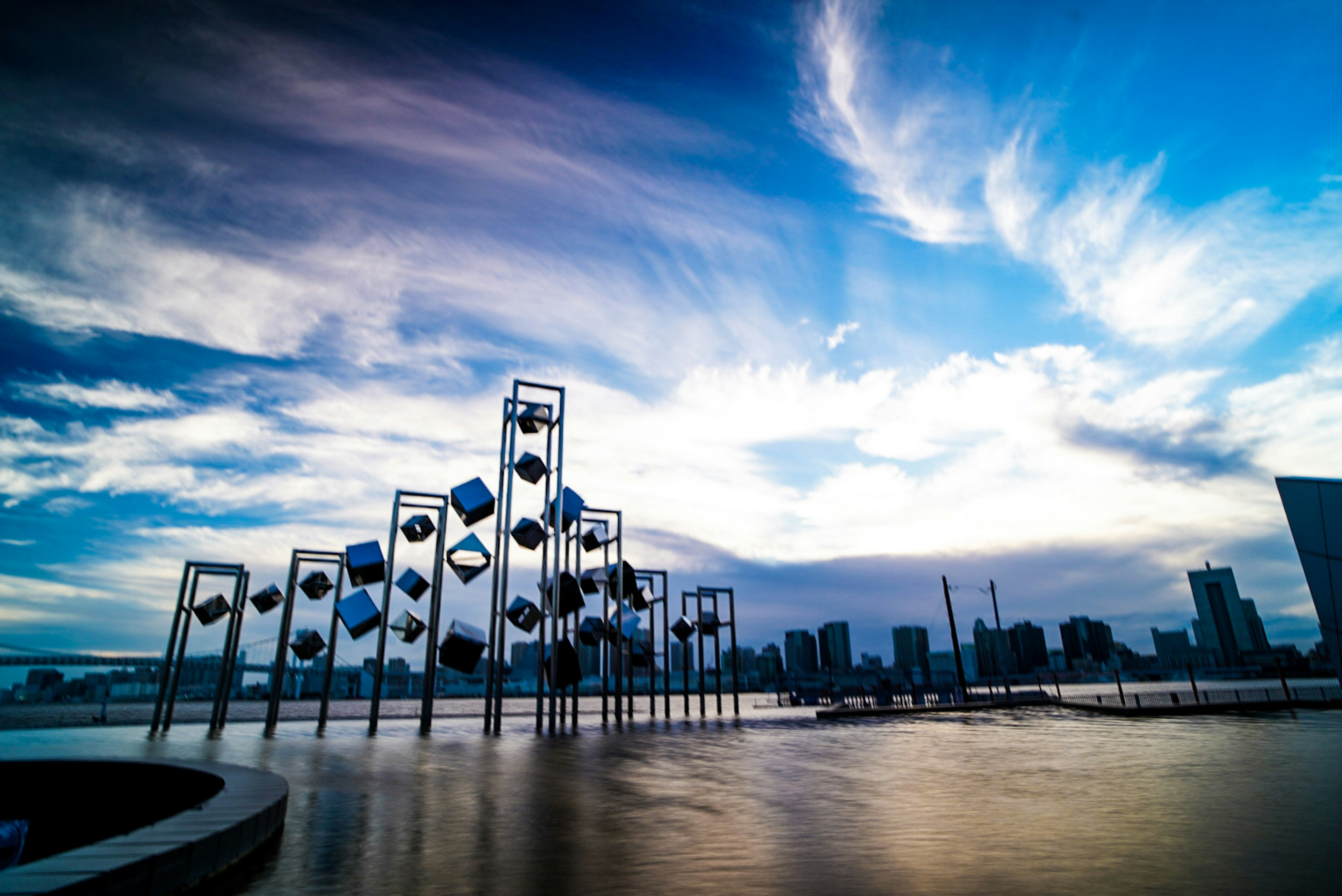 青空と雲の下にあるモダンな彫刻と都市の風景