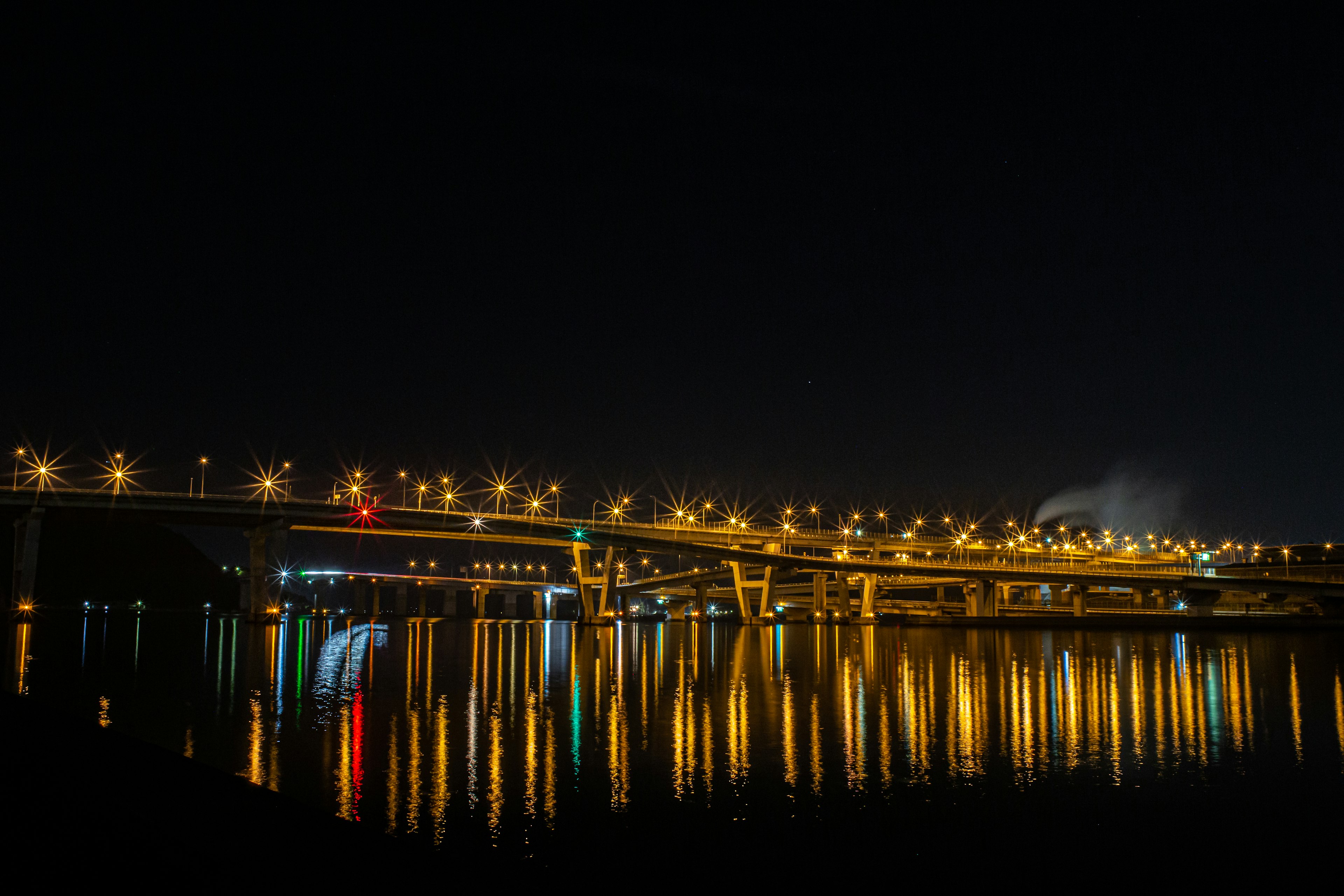 Pemandangan malam jembatan dengan cahaya yang memantul di air