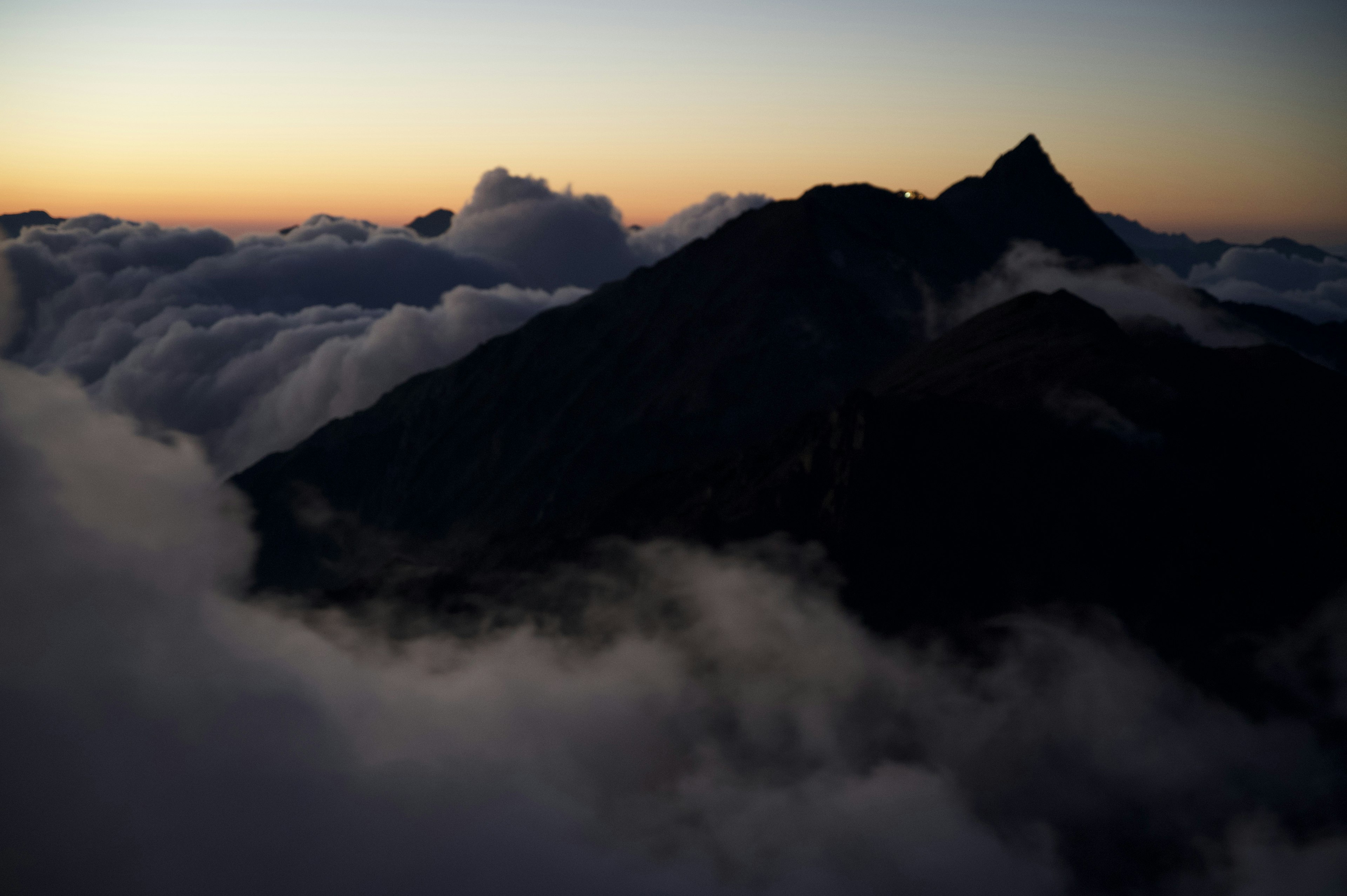 Silhouette d'une montagne au crépuscule entourée de nuages