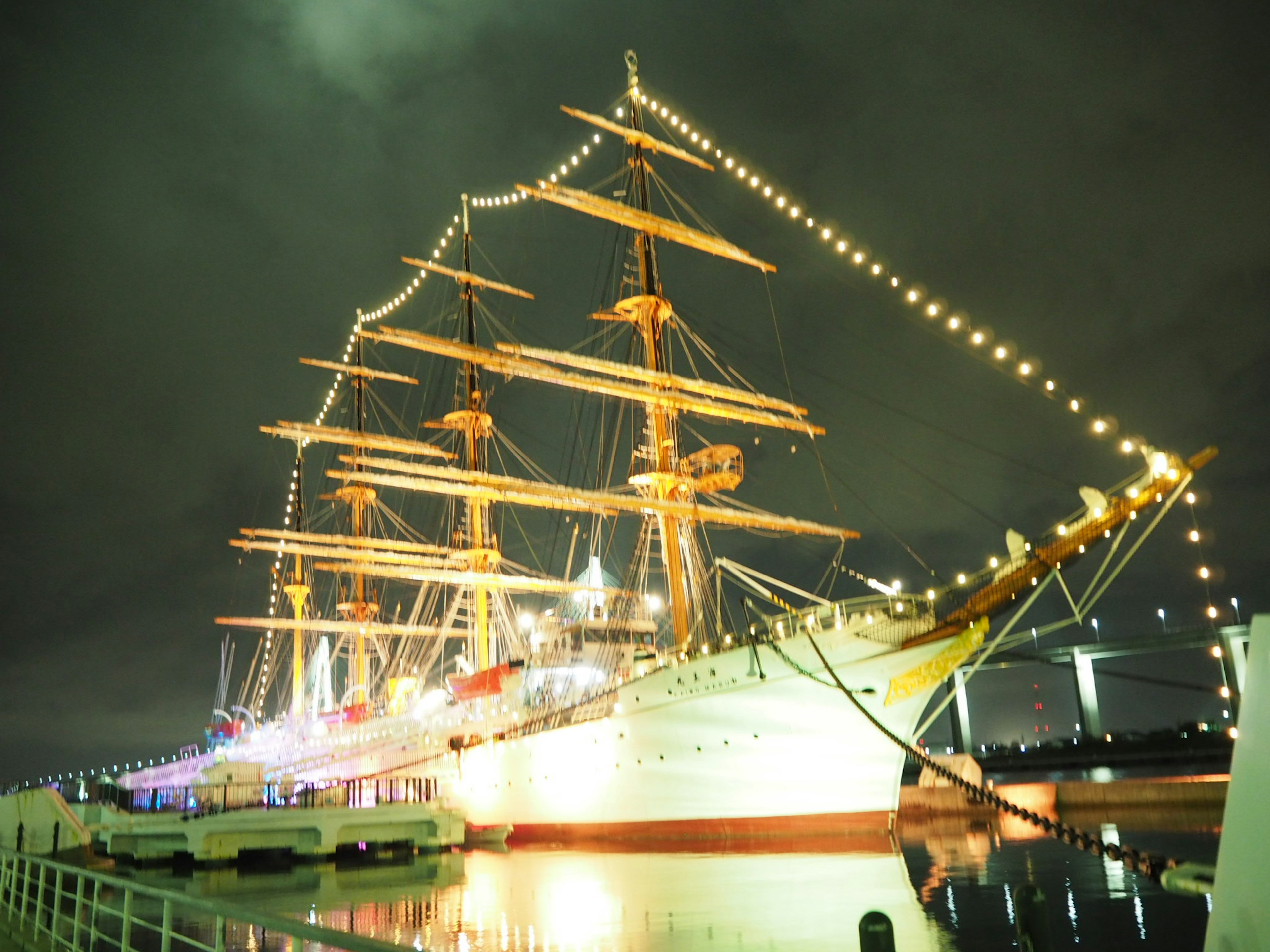 Un hermoso barco de vela iluminado atracado por la noche en el puerto