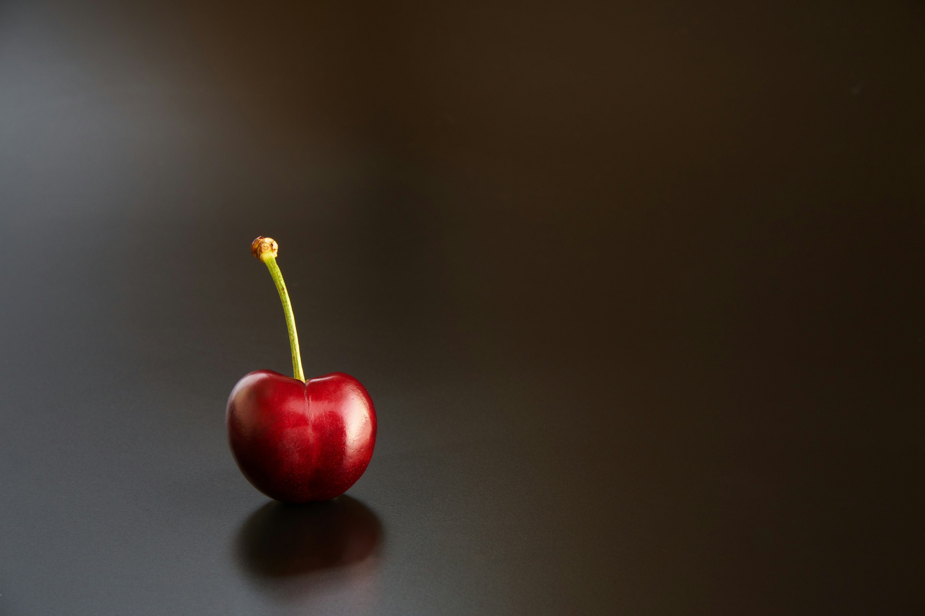 Eine lebhafte rote Kirsche auf einer dunklen Oberfläche