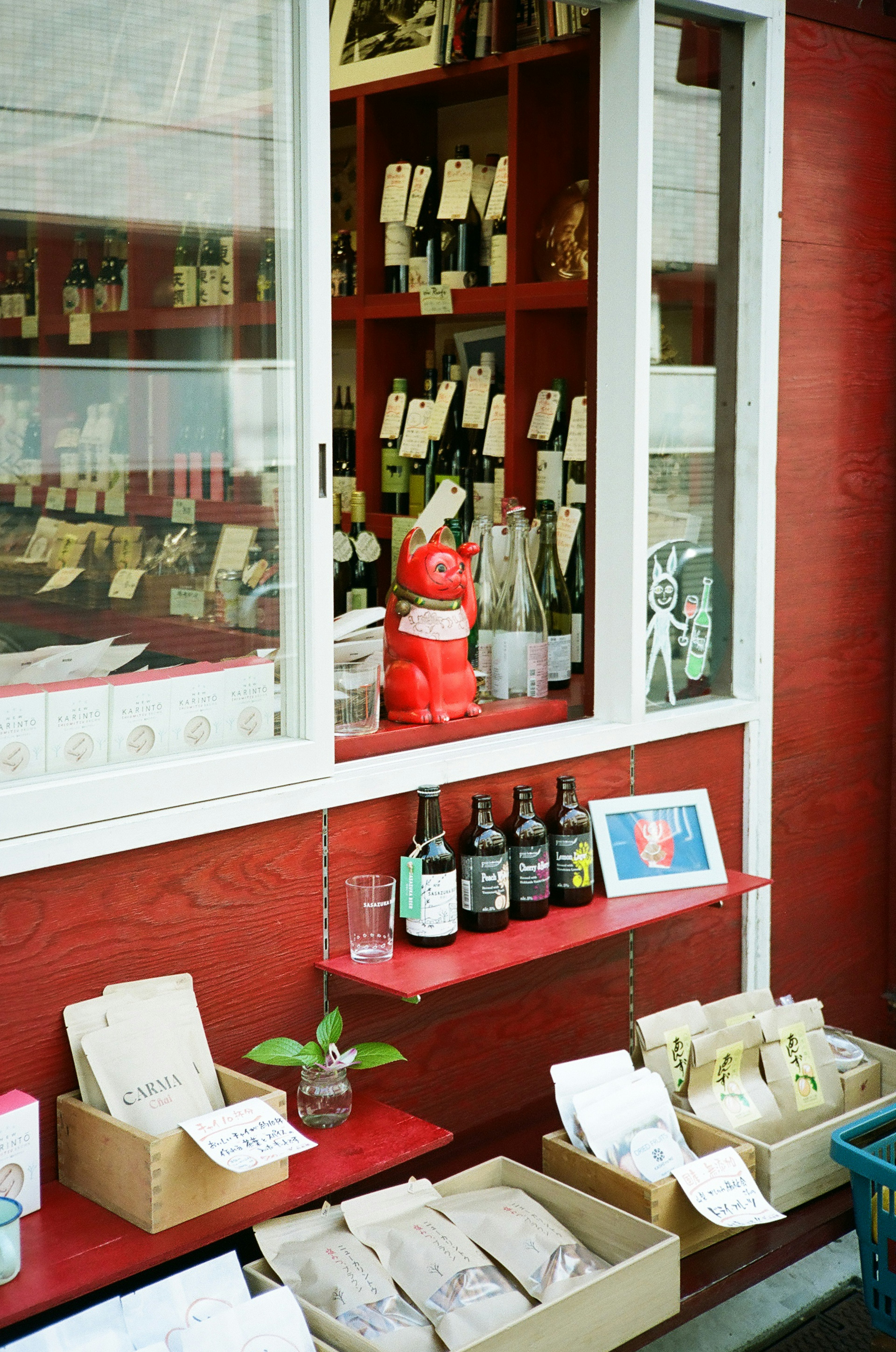 Small shop window with red wall displaying various products and a lucky cat figurine