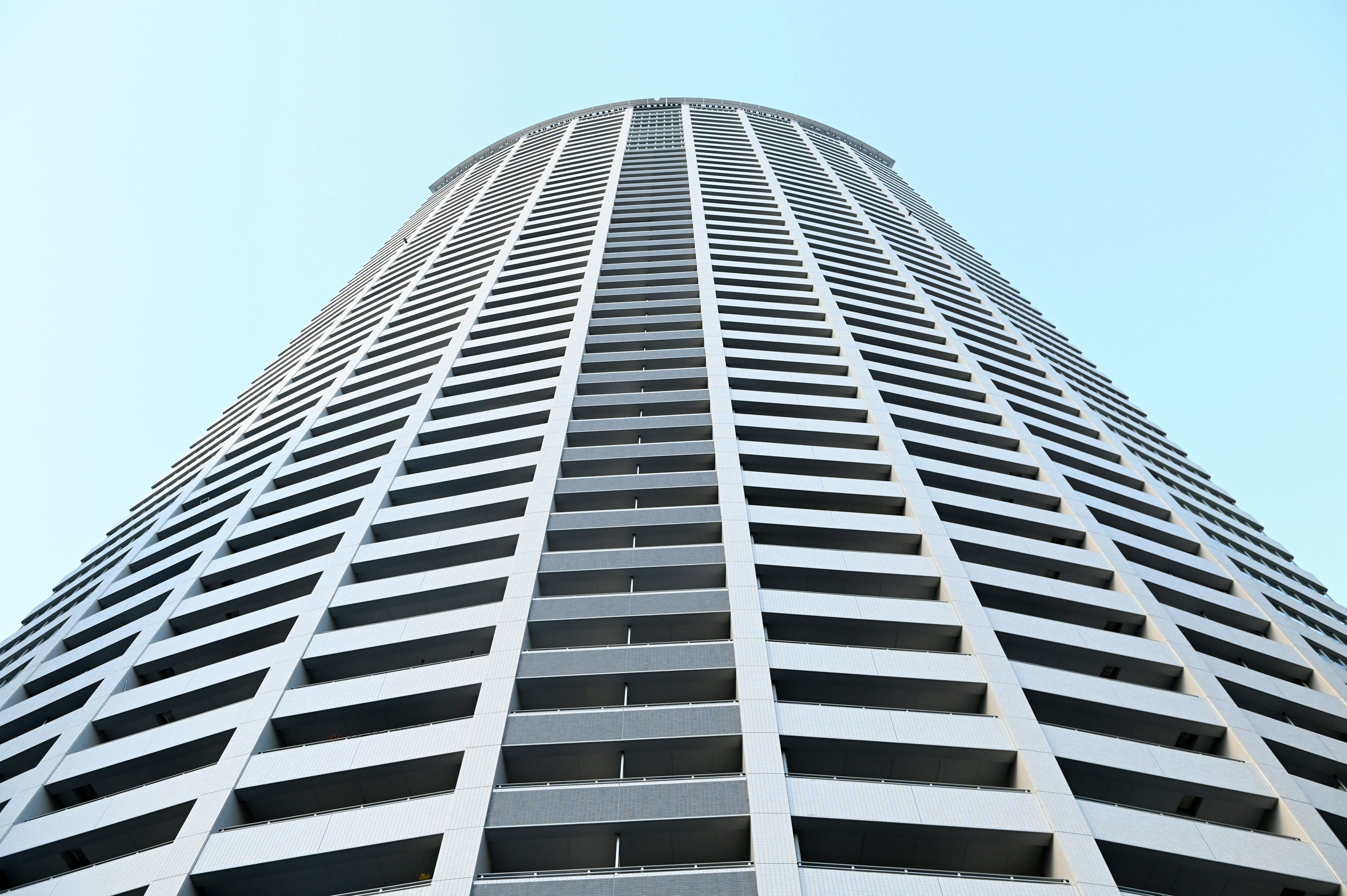 Blick auf ein hohes Gebäude von unten mit klarem blauen Himmel