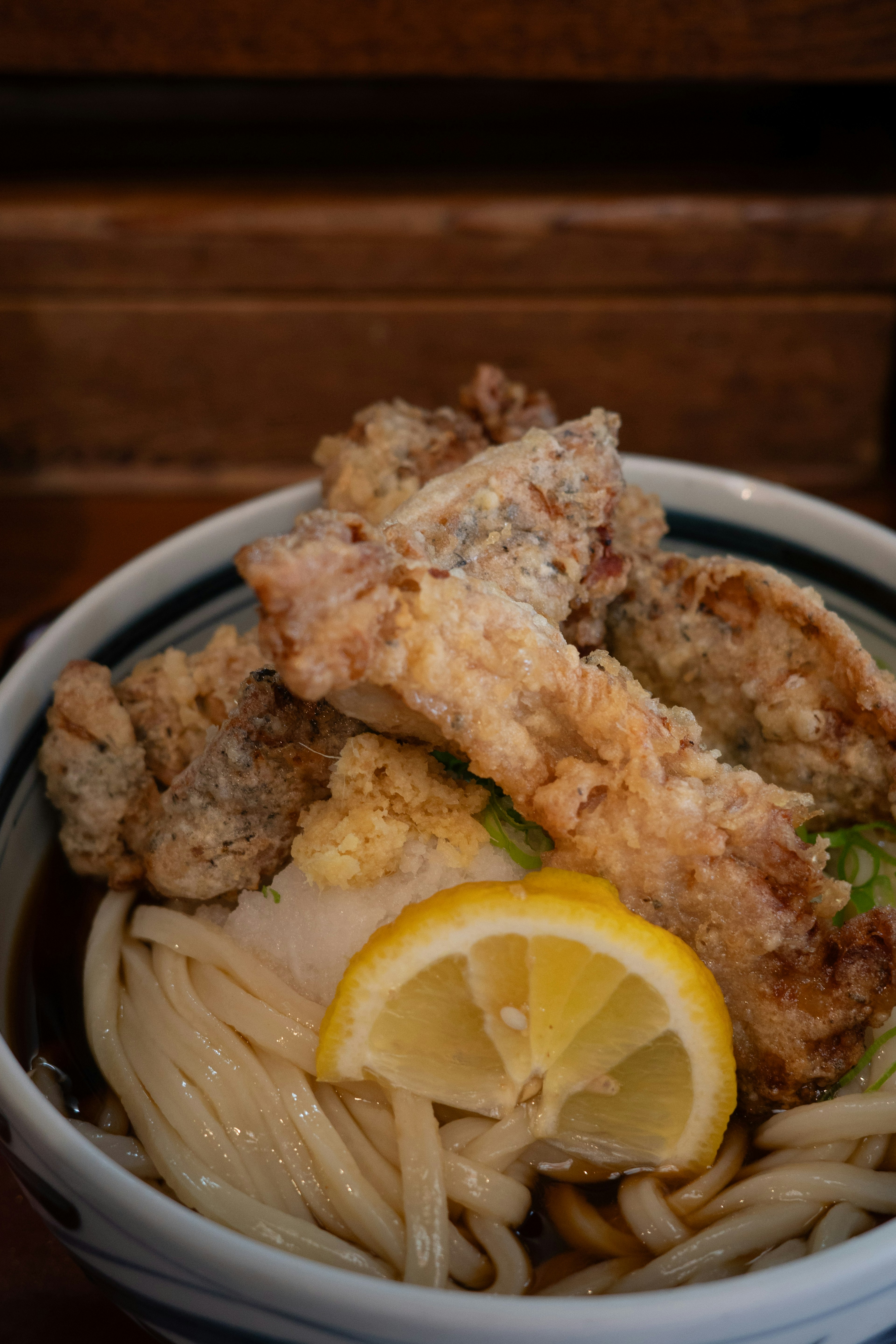 Mangkuk udon lezat dengan tempura dan lemon di atasnya