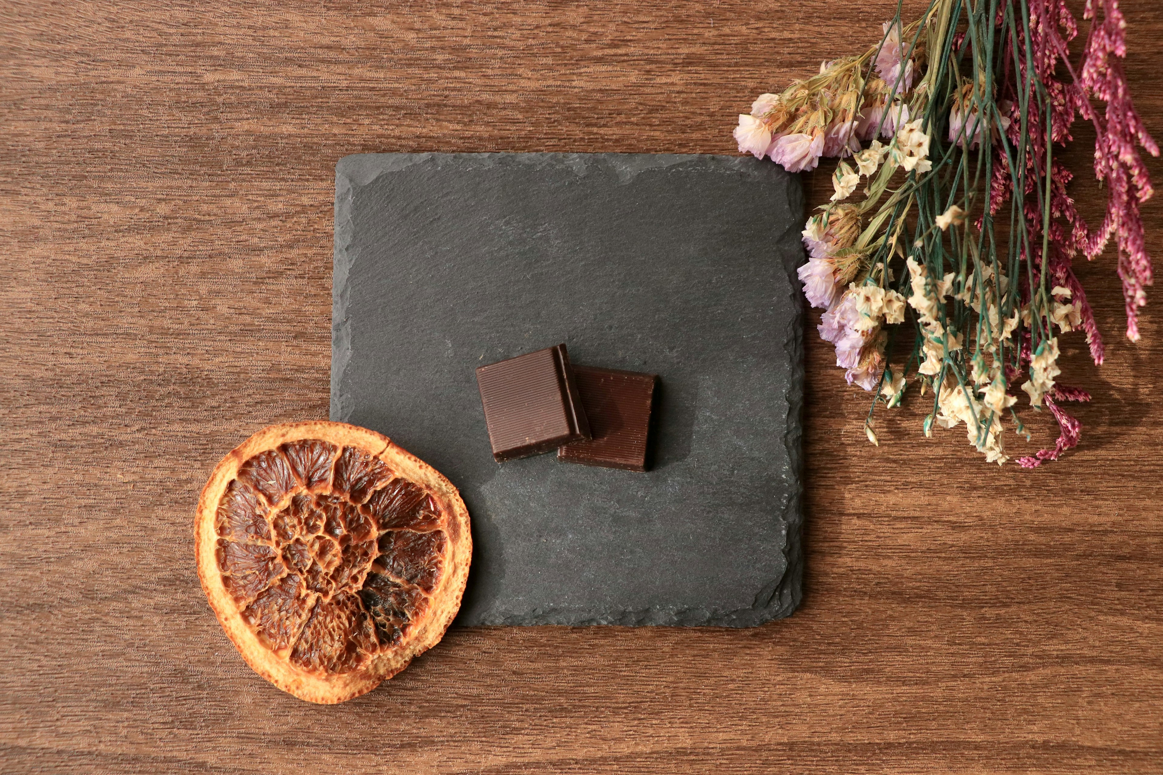 Hermosa disposición de chocolate y una rodaja de naranja seca sobre una tabla de pizarra negra