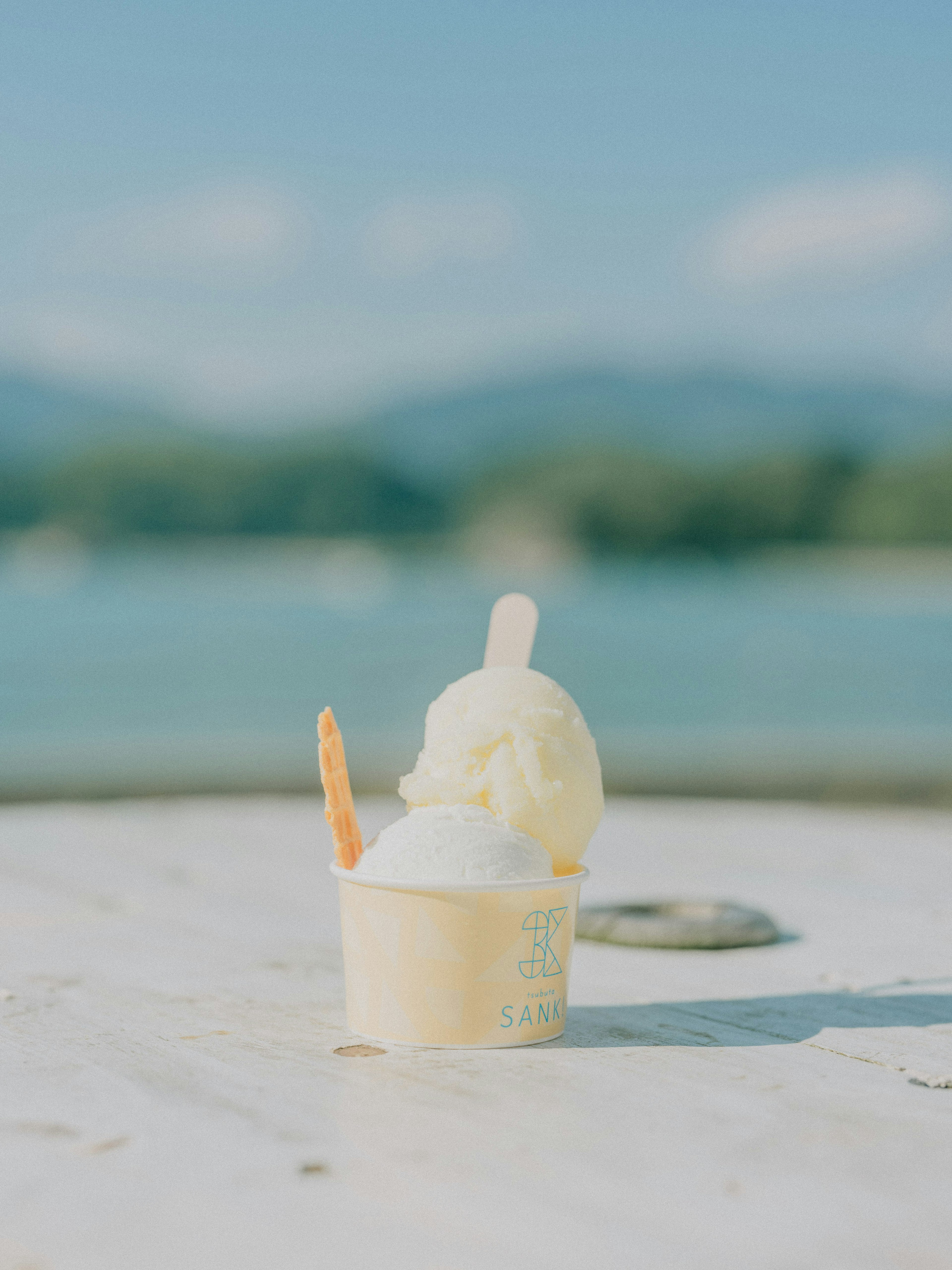 Cangkir es krim dengan dua skop di depan laut biru dan pegunungan