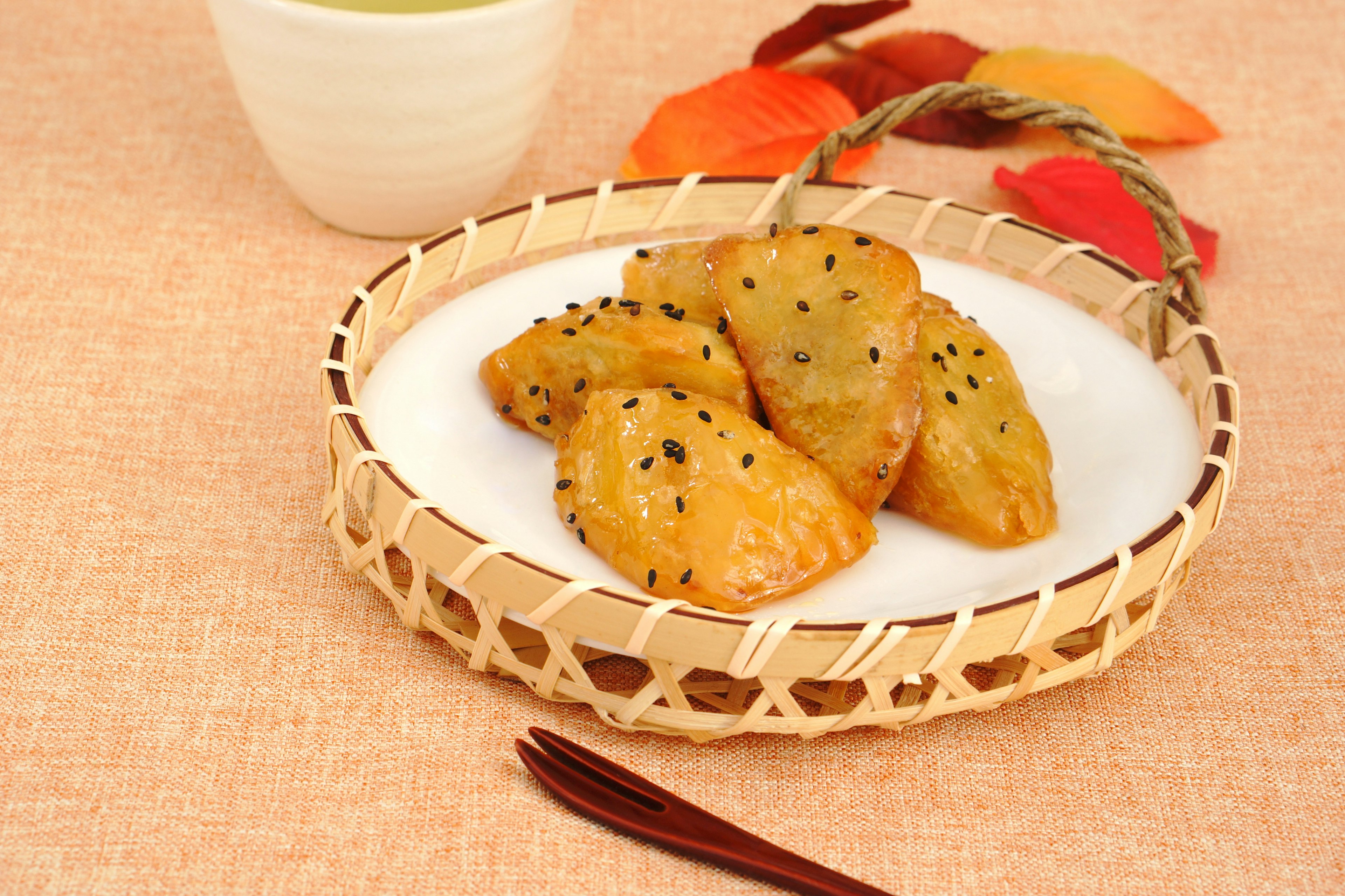 Fried dumplings arranged on a bamboo plate with a cup of green tea