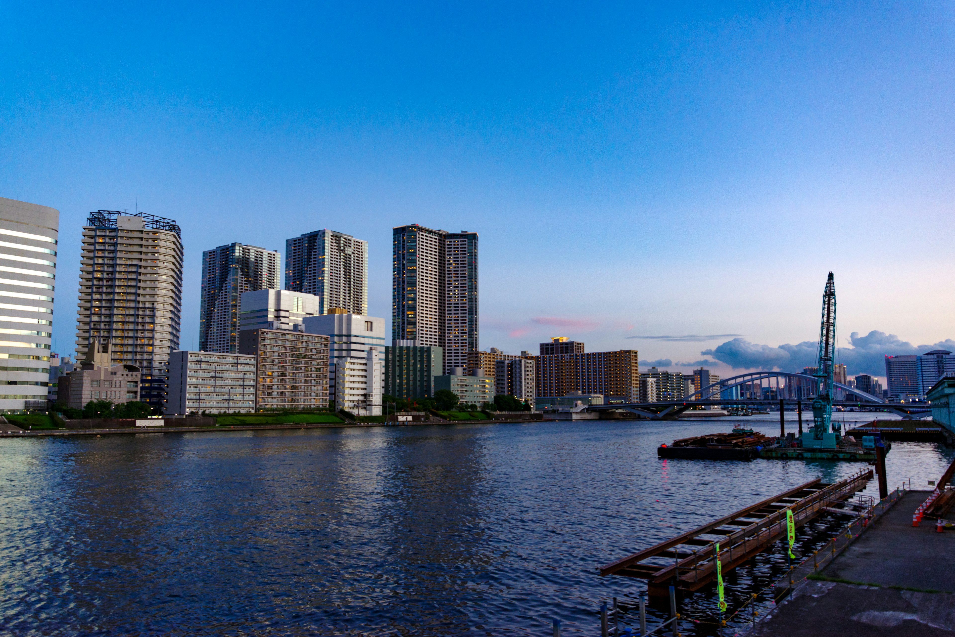 City skyline with modern buildings along a river under a blue sky