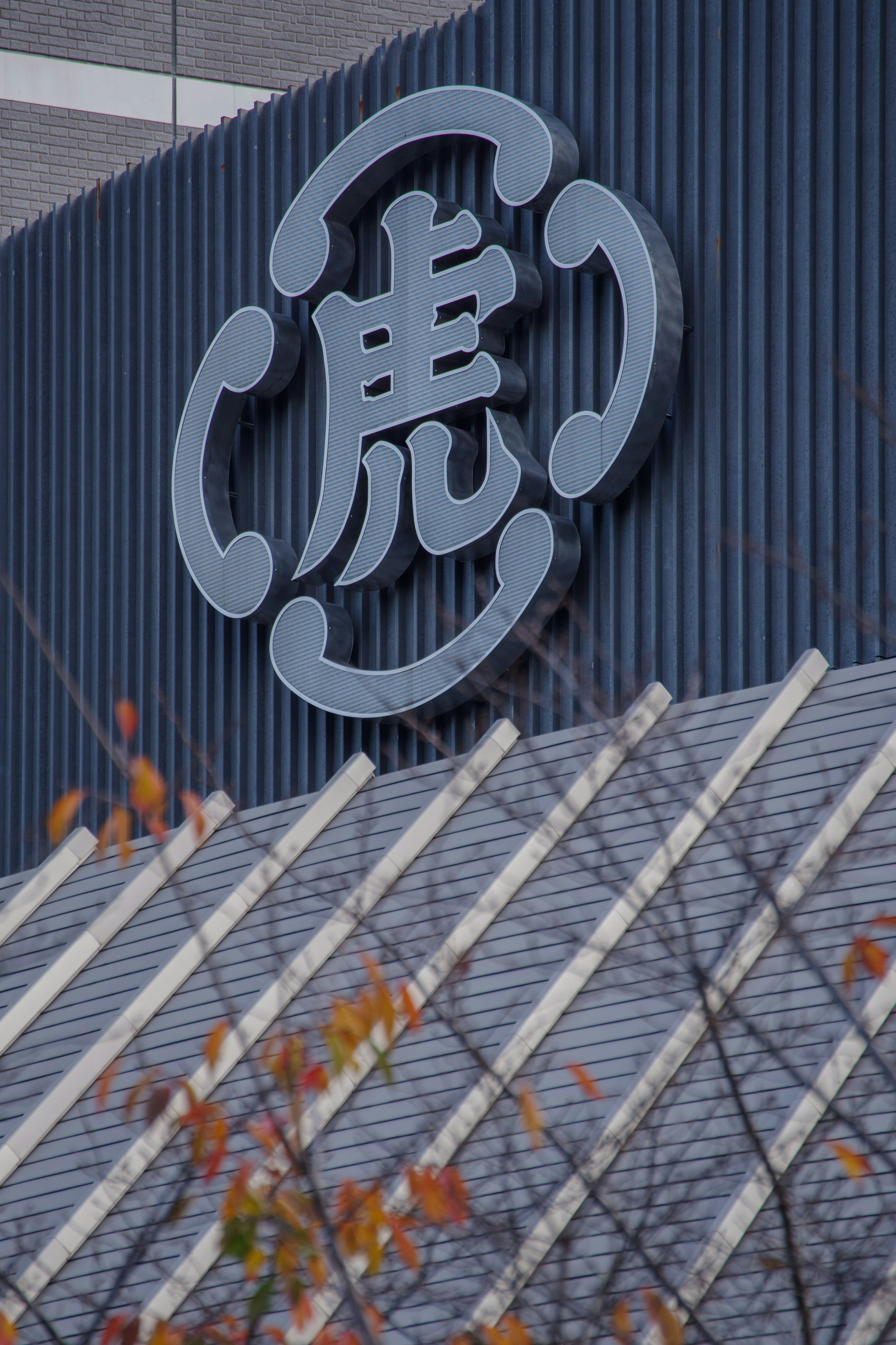 Tiger logo on a blue wall with autumn leaves