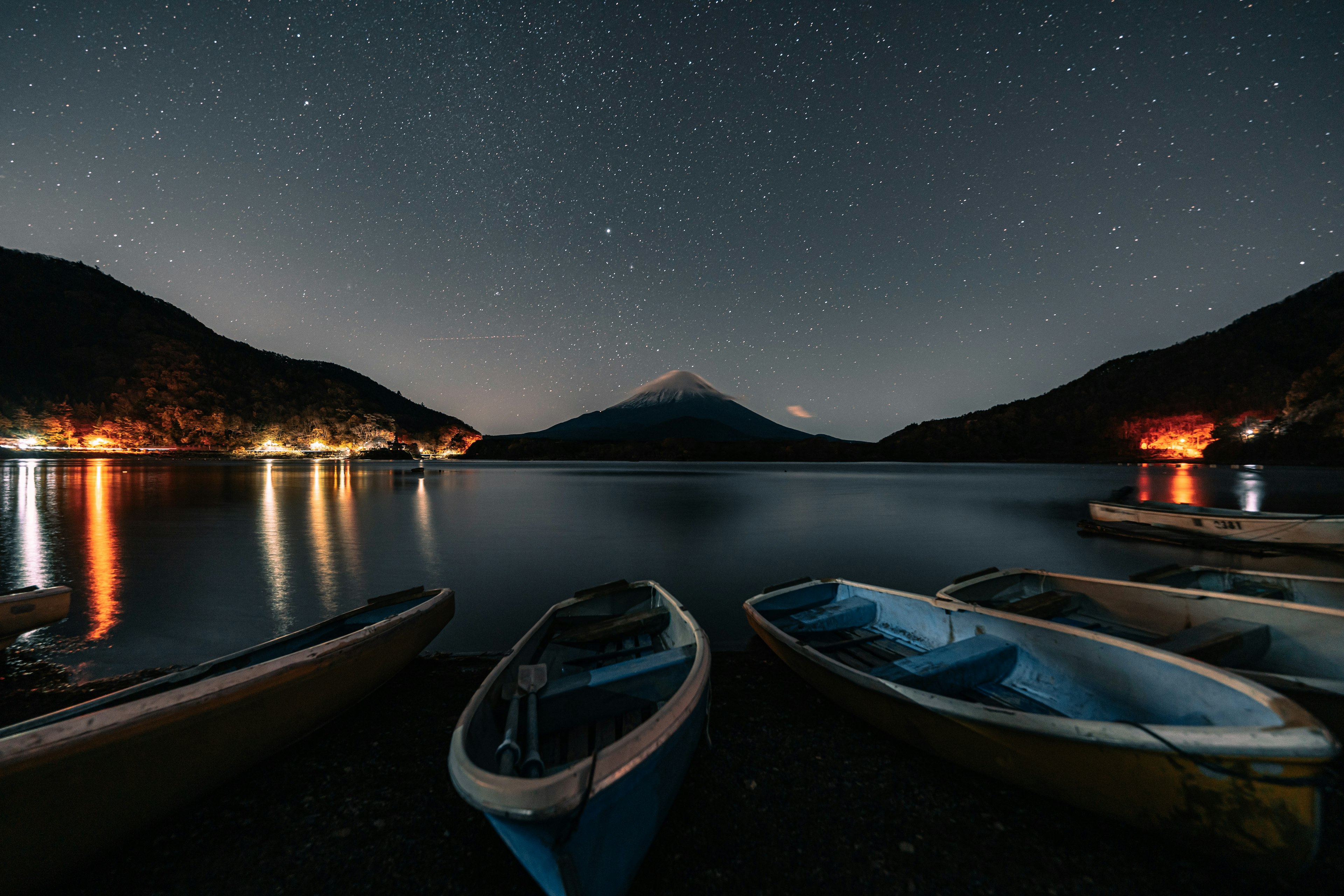 Bateaux sur la rive sous un ciel étoilé avec silhouette de montagne