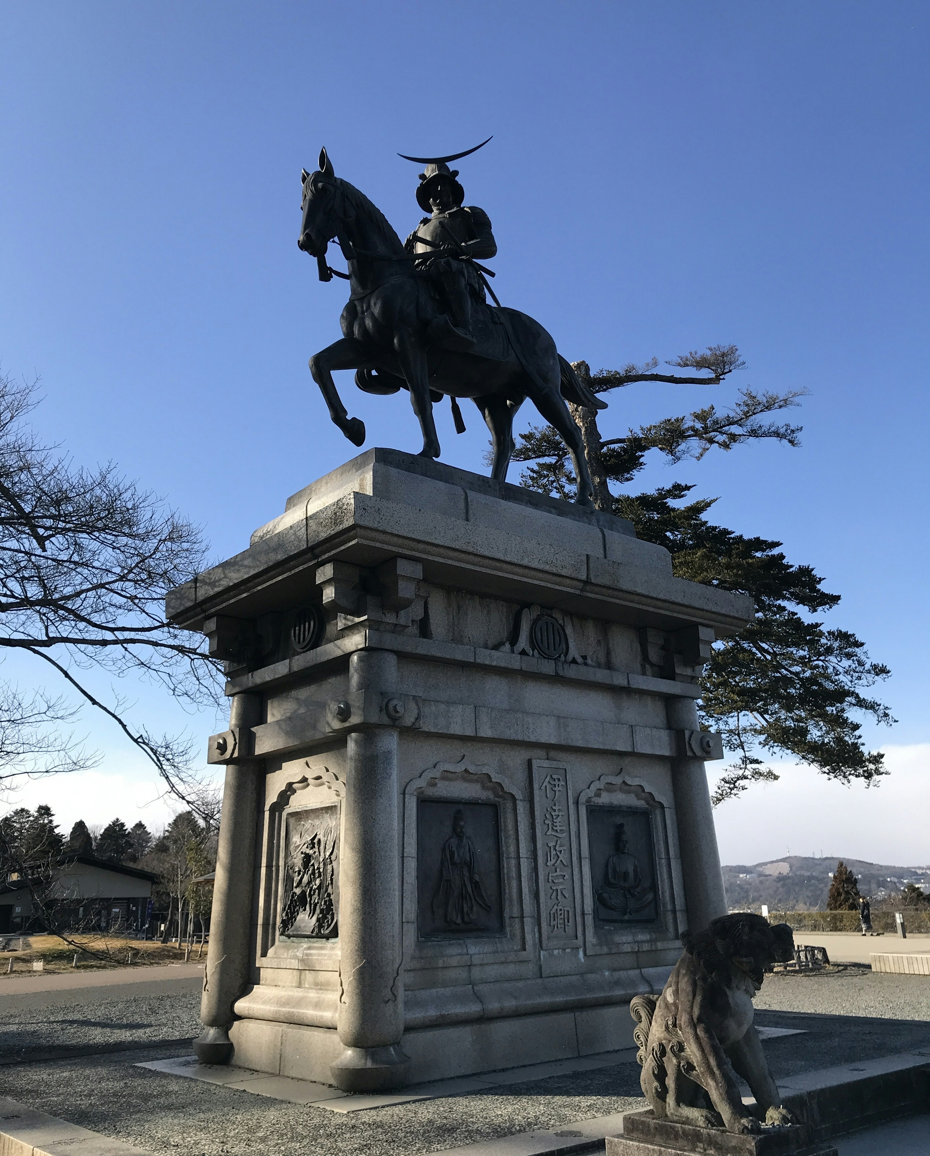 Bronze statue of a samurai on horseback under a blue sky