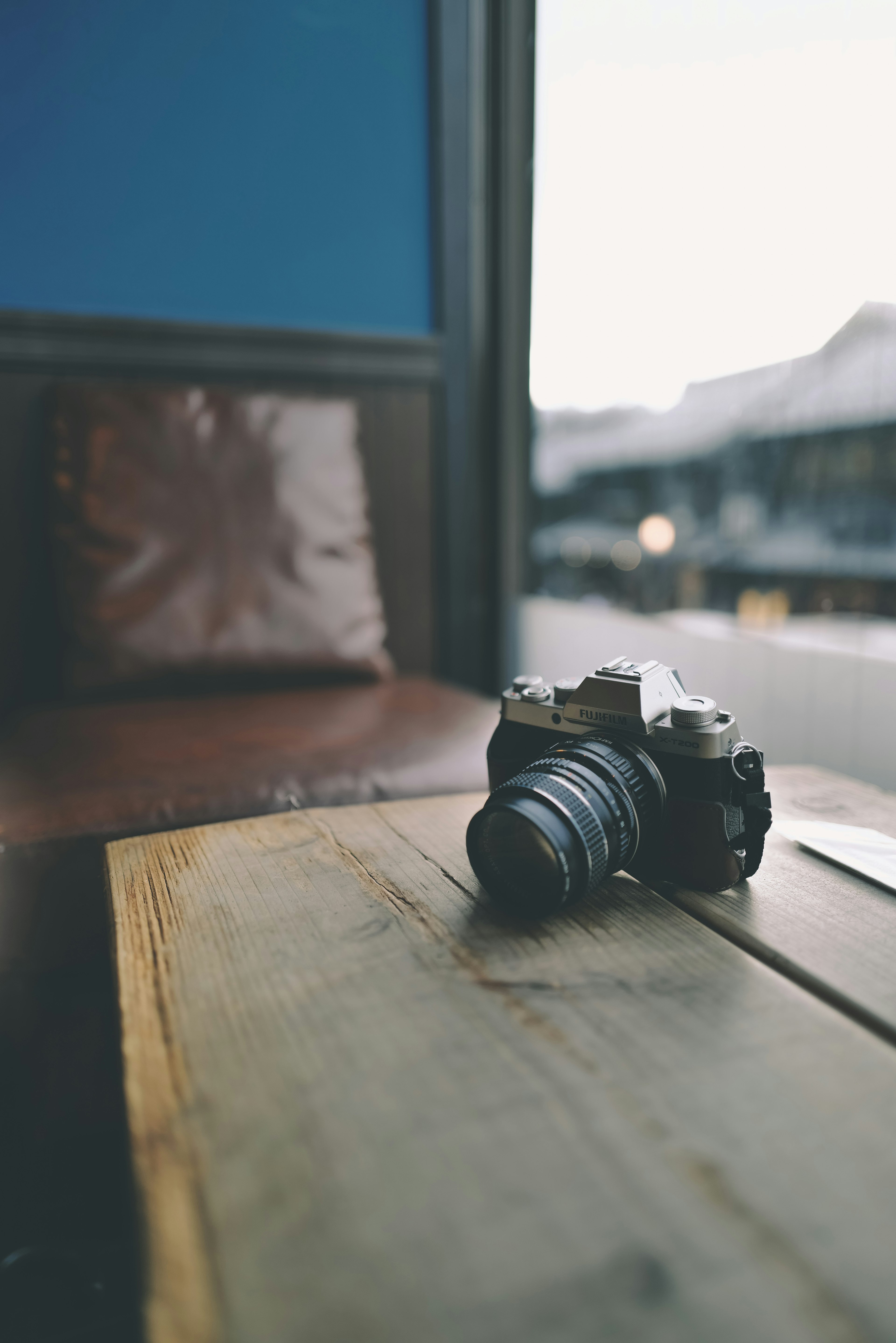 Camera placed on a wooden table with a blue wall in the background