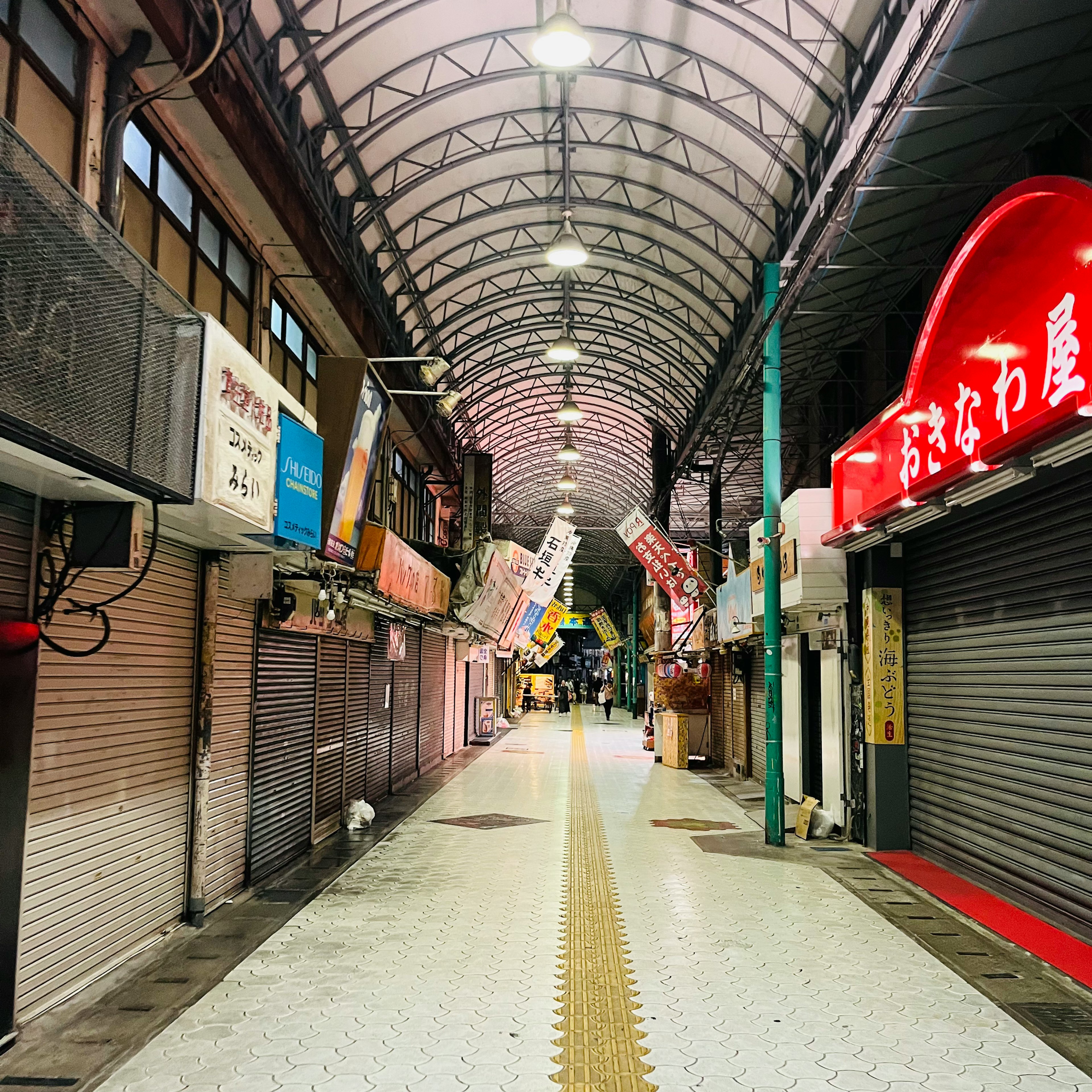 空いている商店街の通り 明るい照明と閉じたシャッターの店舗