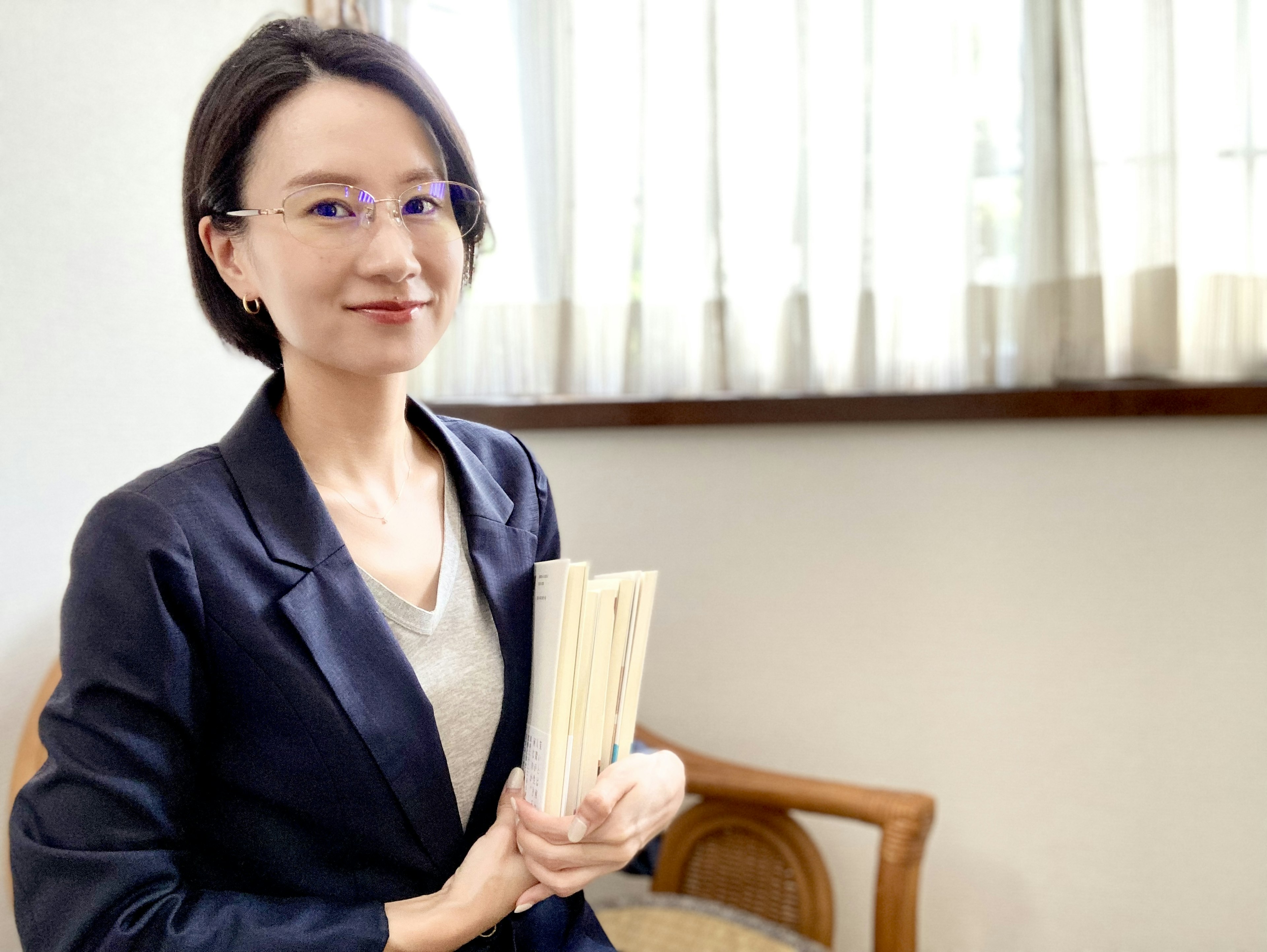 A woman smiling while holding books in an indoor setting