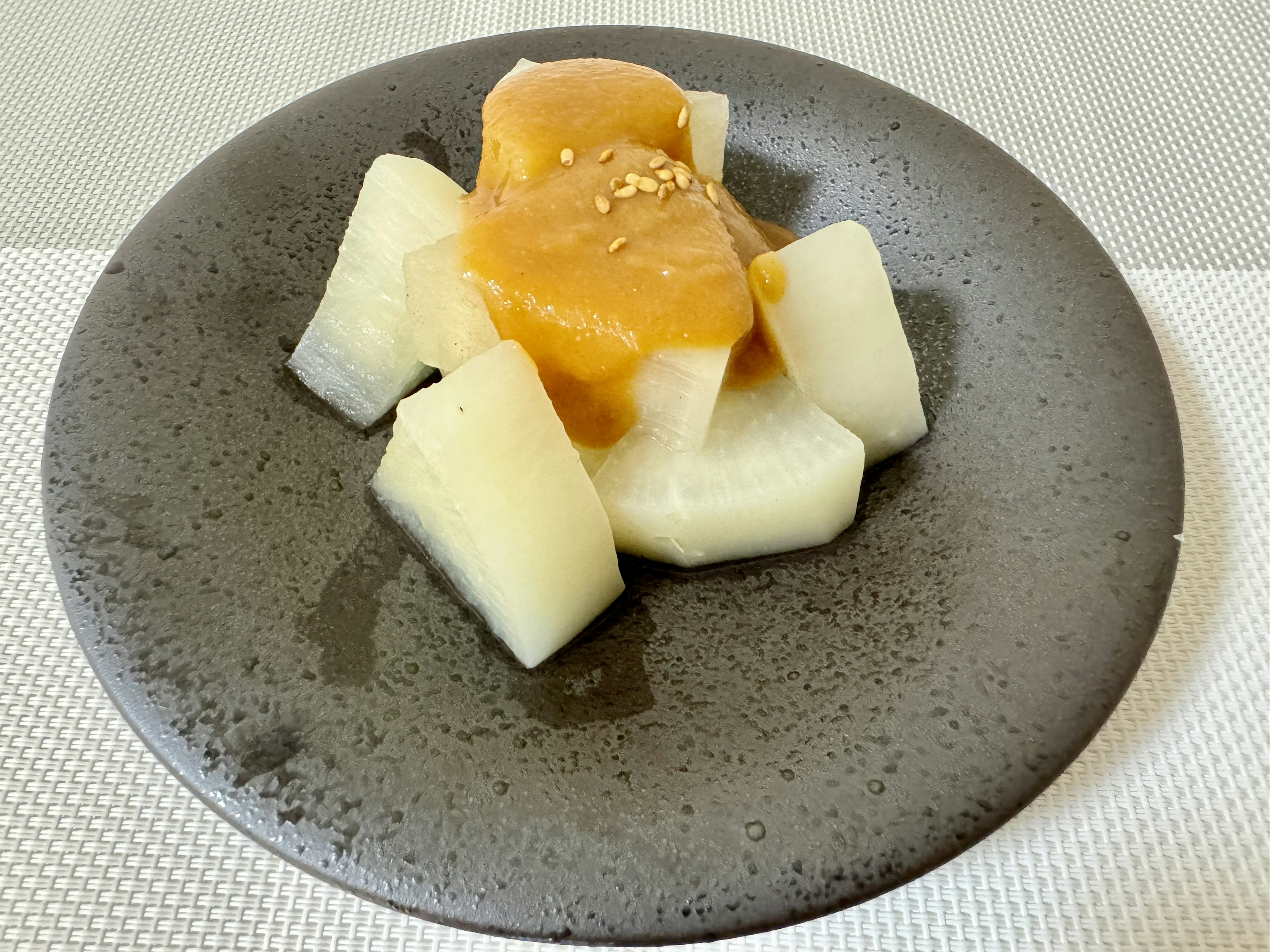 Dessert aus Melonenstücken mit süßer Sauce auf einem grauen Teller