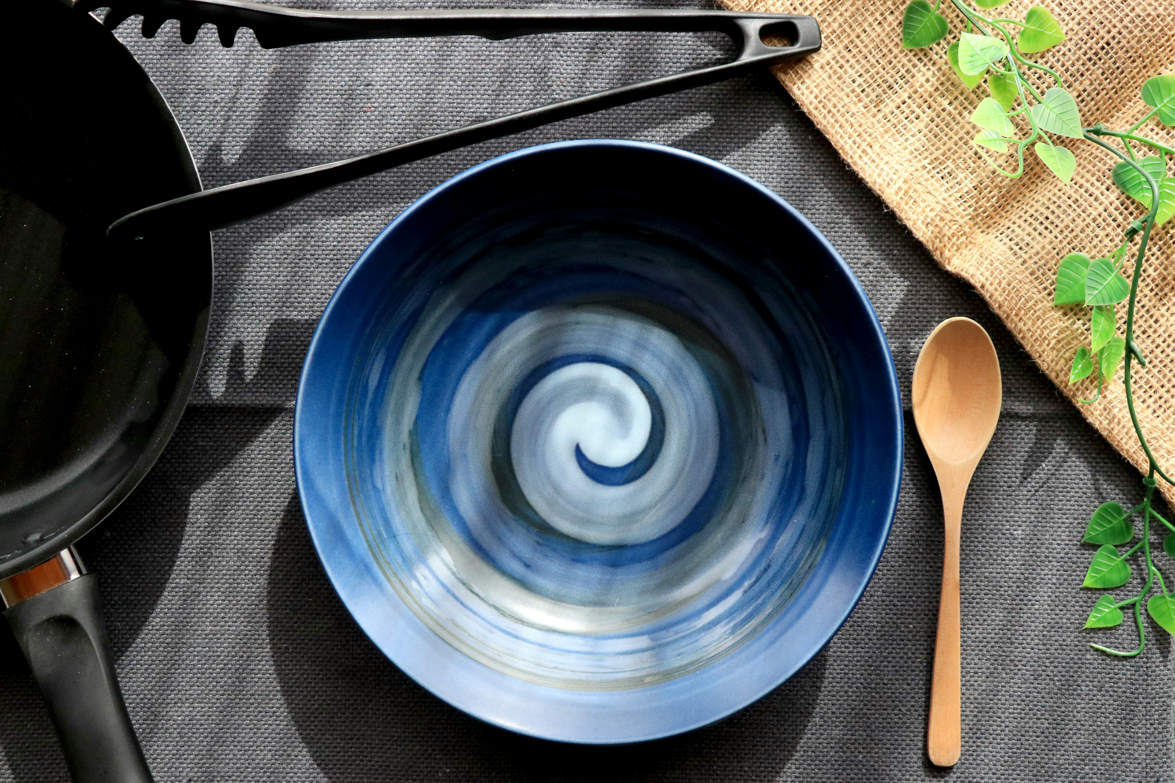 Blue swirl patterned bowl with a wooden spoon on a table setting