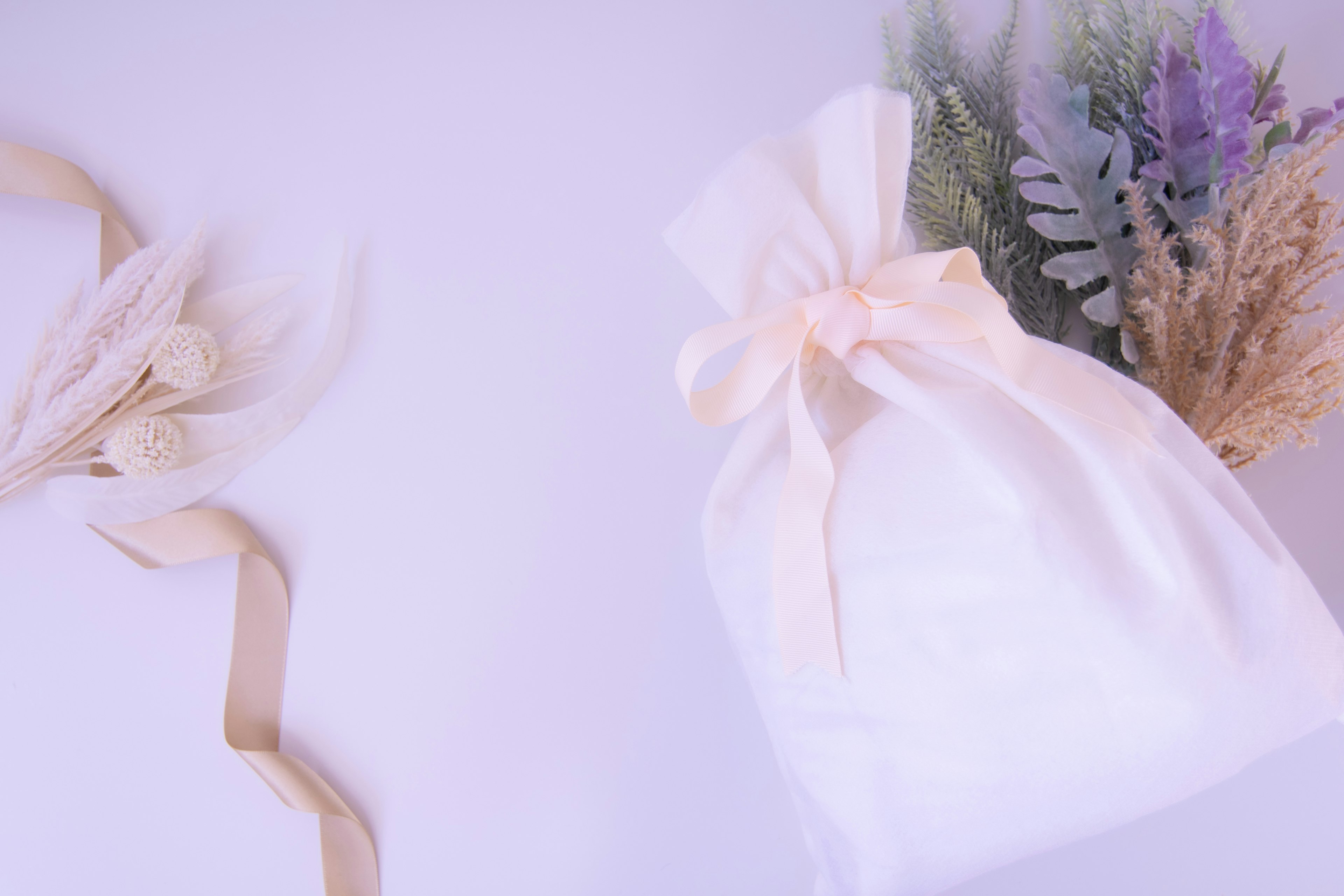 Sac en tissu blanc avec un ruban et bouquet de fleurs séchées