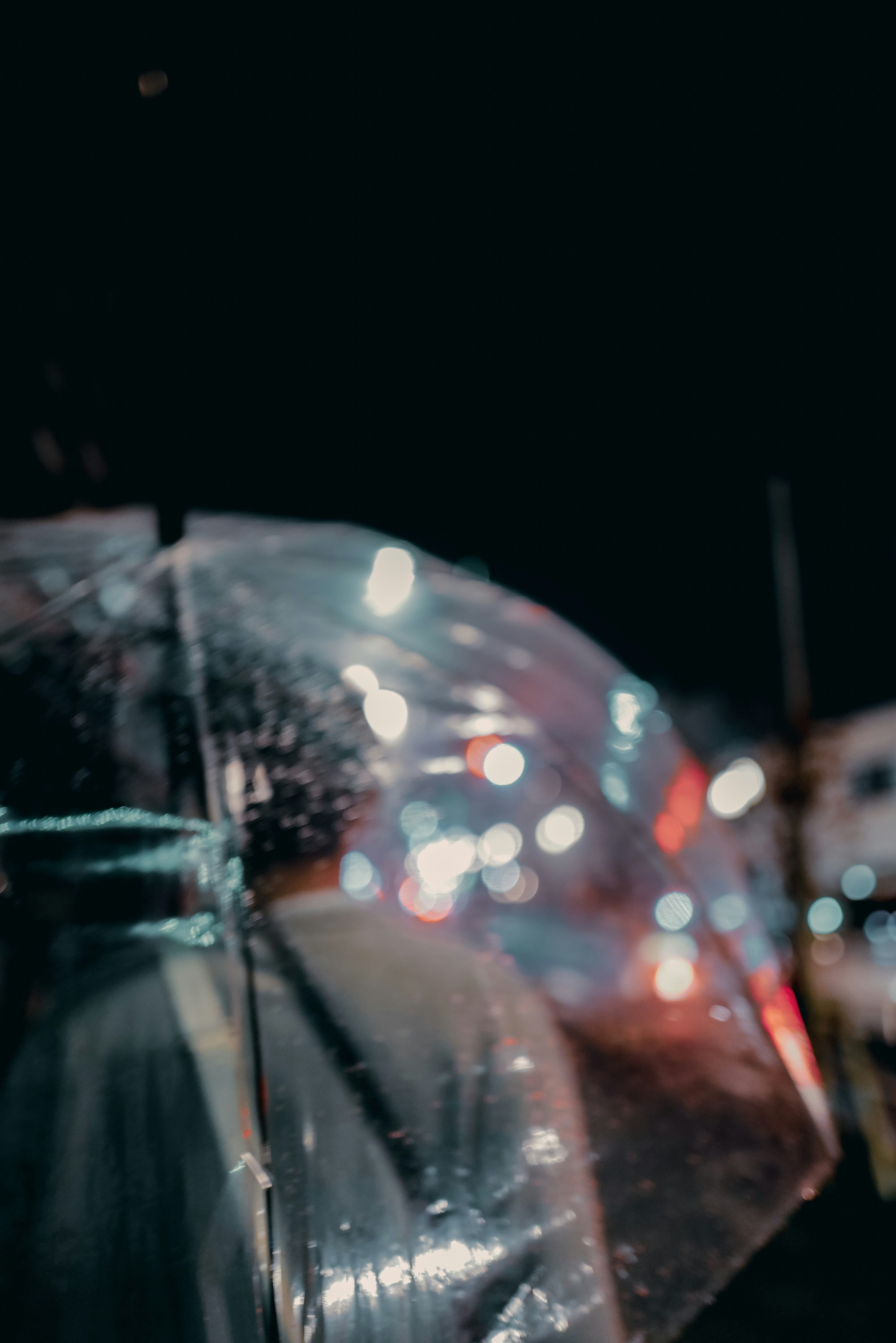 Close-up of a transparent umbrella reflecting city lights at night