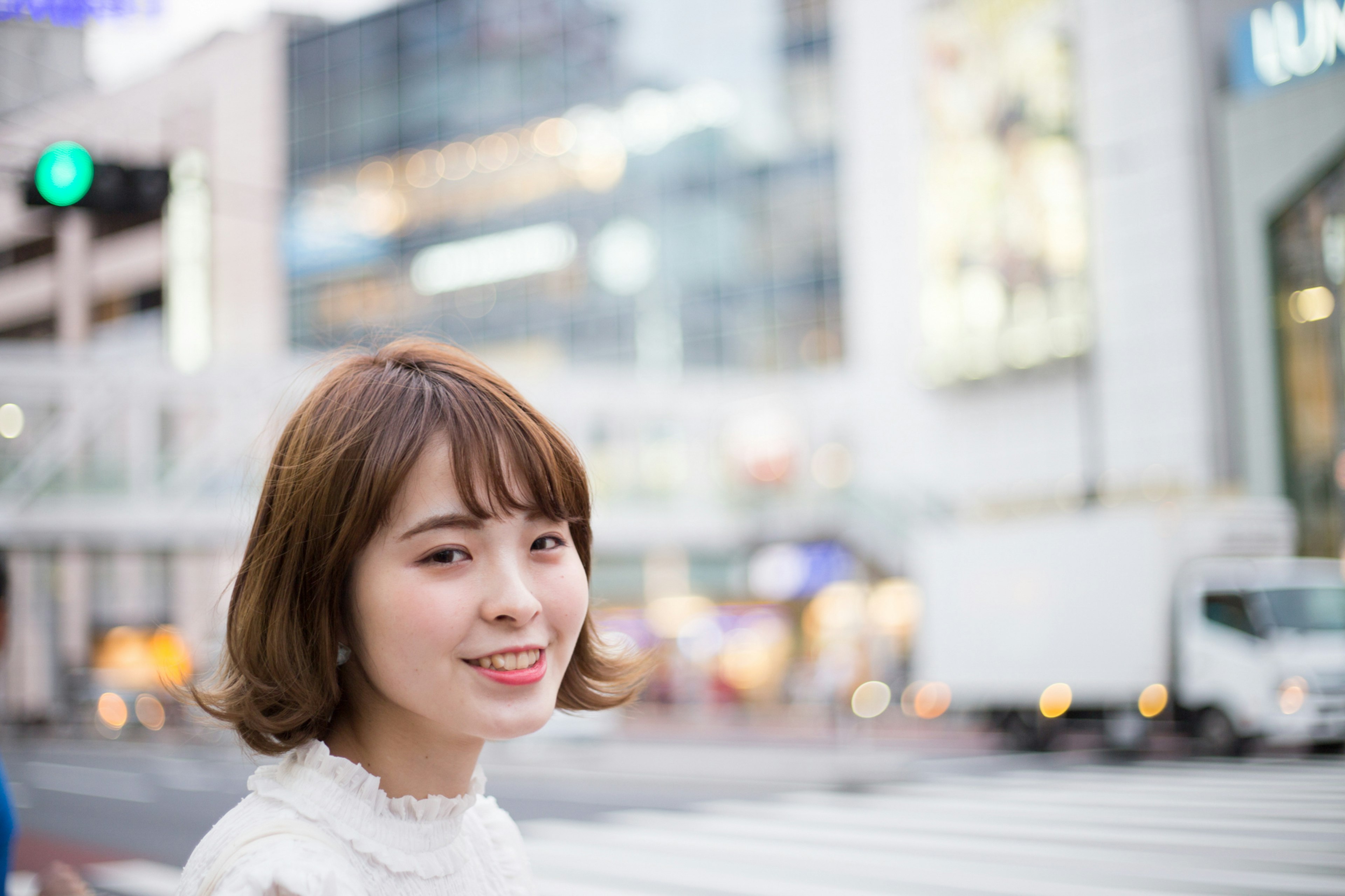 A woman smiling in the city street with urban buildings in the background