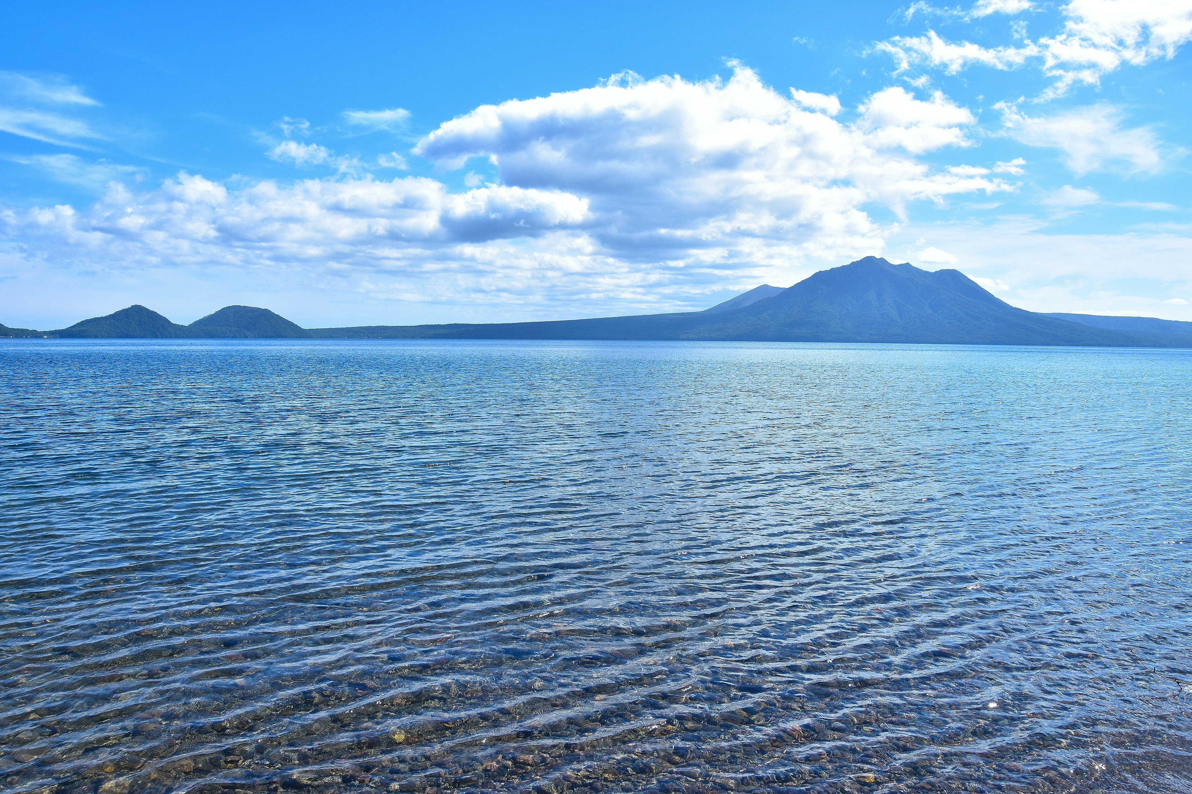 藍色湖泊的風景 遠處有山和波紋的水面