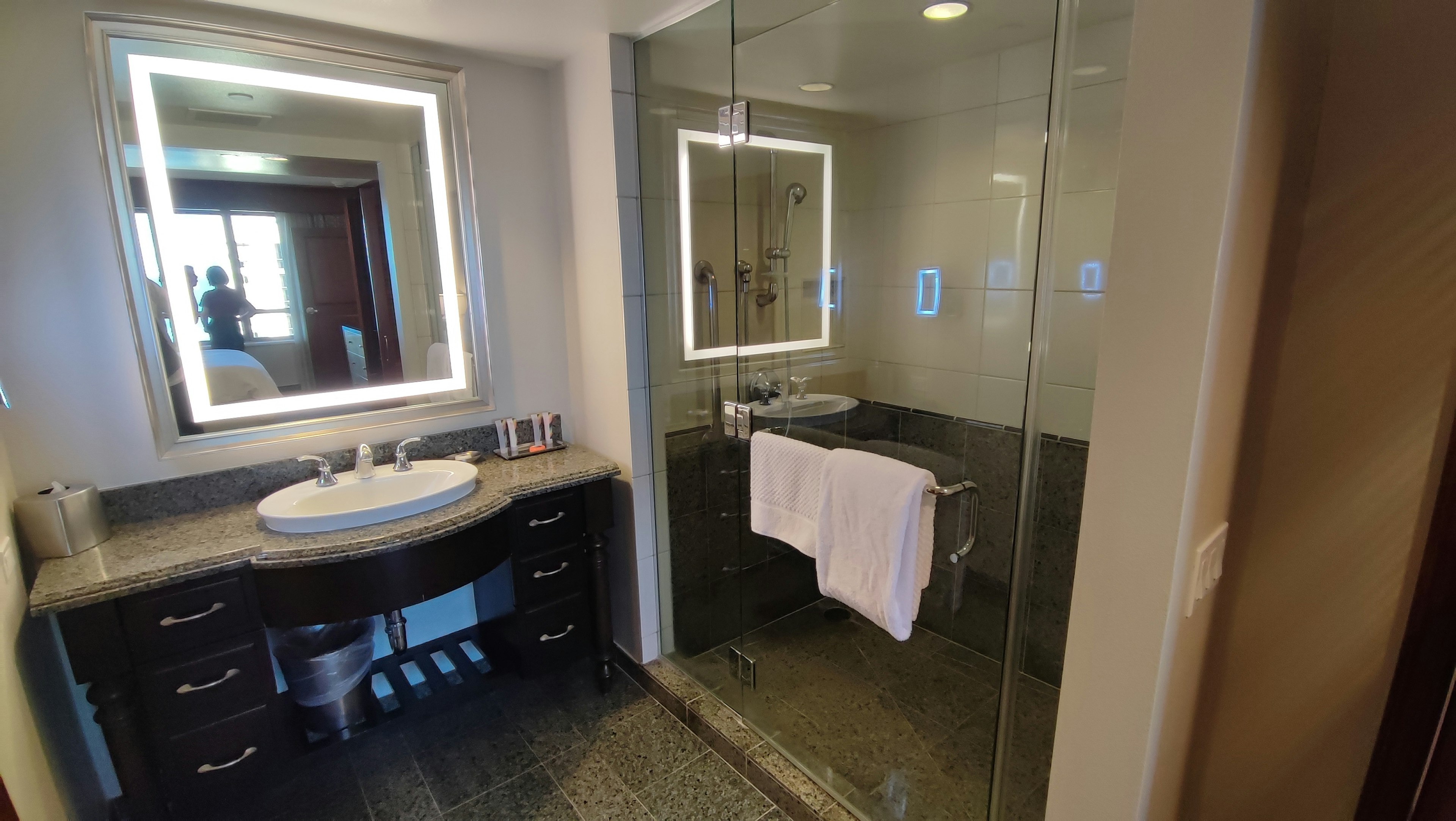 Modernes Badezimmerinterieur mit elegantem Waschbecken Glasdusche beleuchteter Spiegel