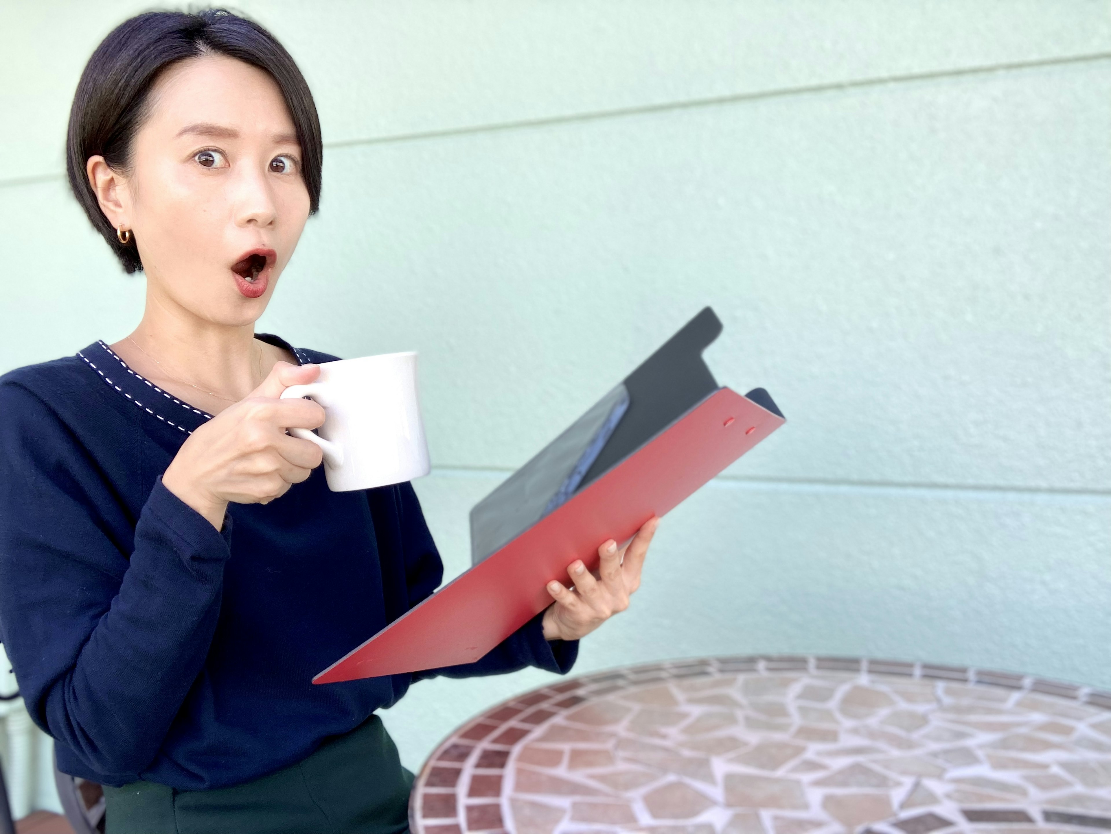 Donna sorpresa che tiene un menù mentre beve un caffè in un caffè