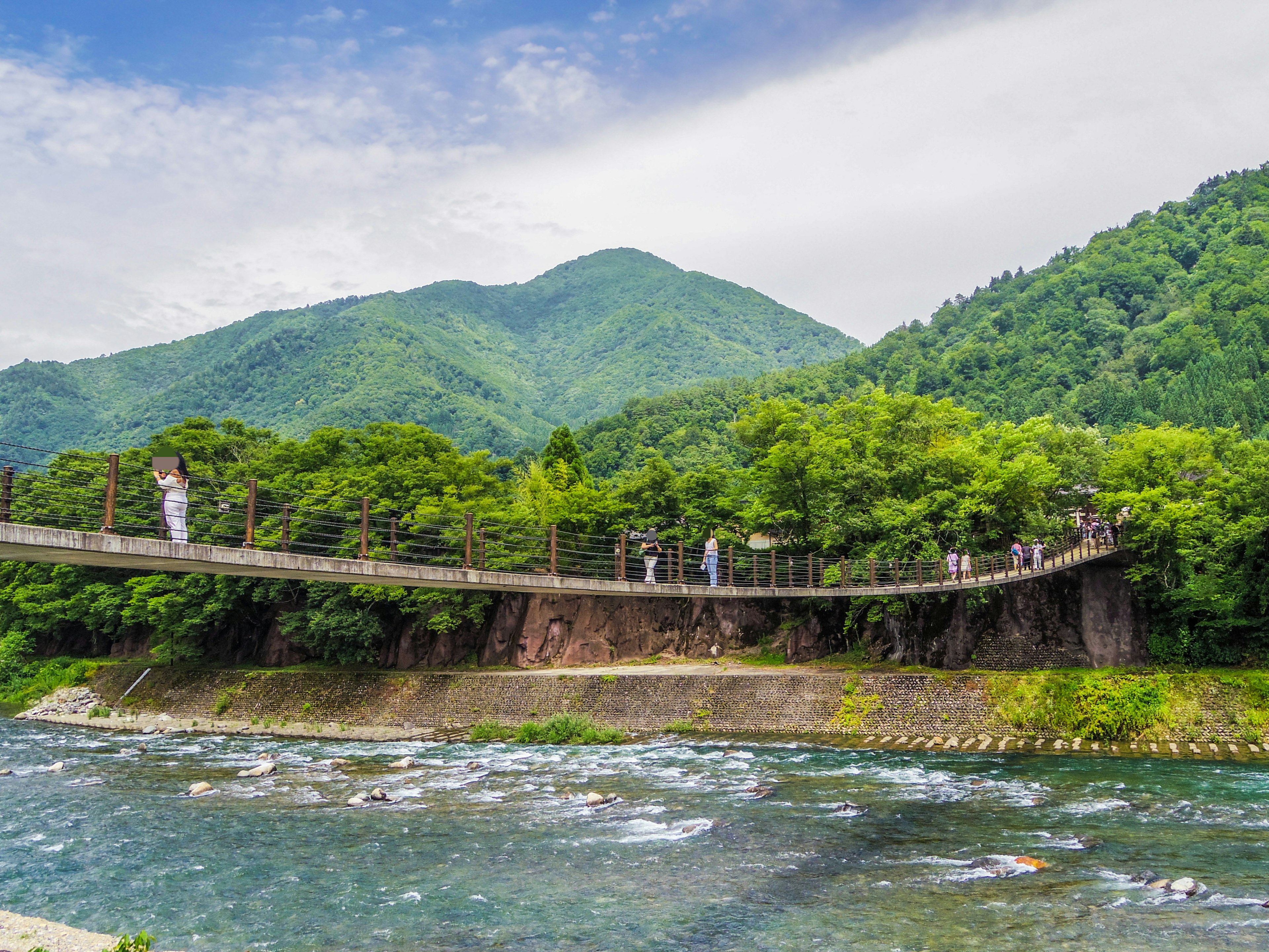 วิวสวยของสะพานไม้ข้ามแม่น้ำที่มีภูเขาเขียวขจีล้อมรอบ