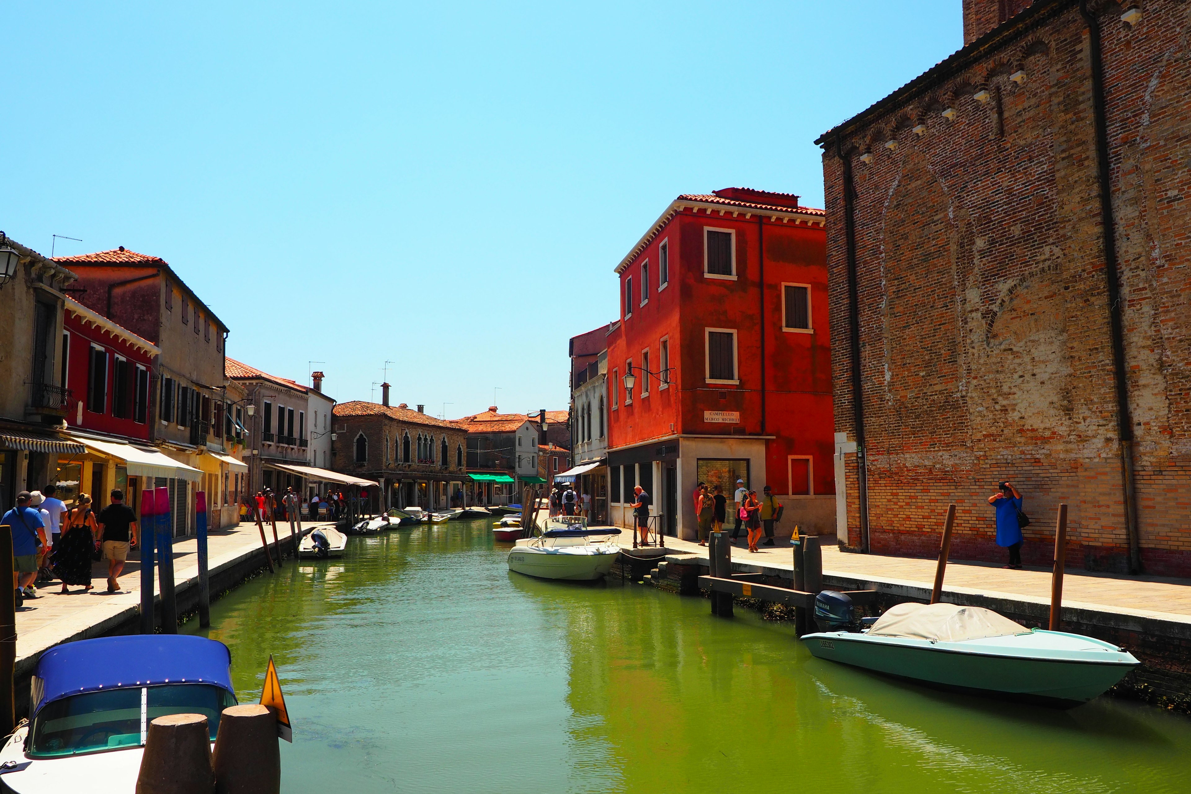 Colorful buildings and boats along a canal under a bright blue sky