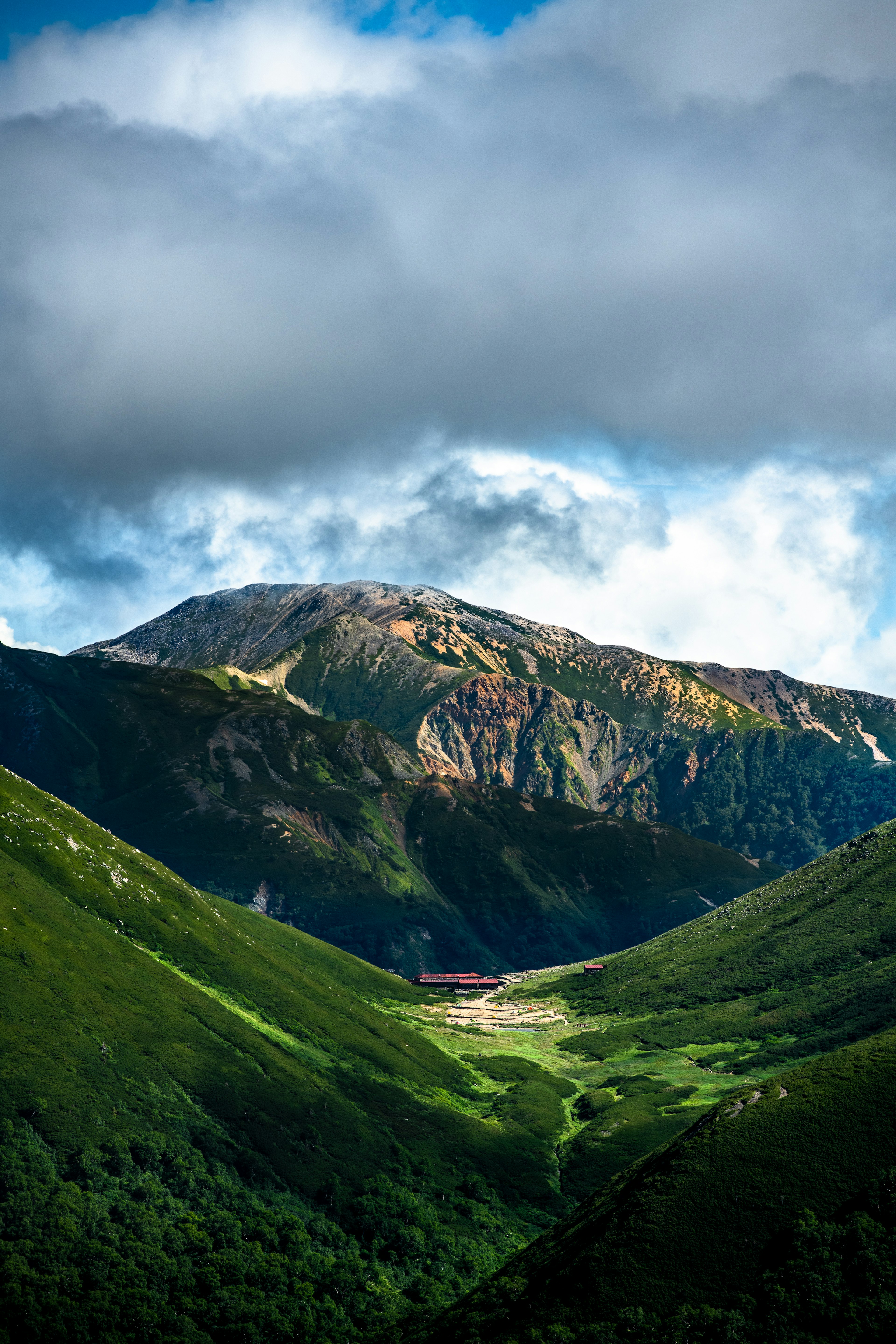 緑の谷と山々に囲まれた風景、青空と雲が広がる