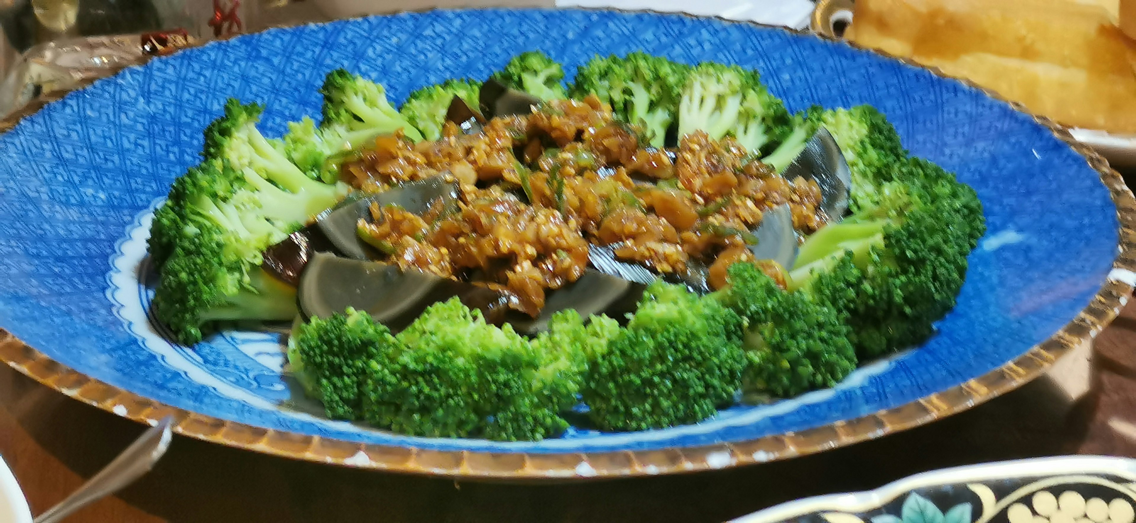 Dish of broccoli surrounding minced meat on a blue plate