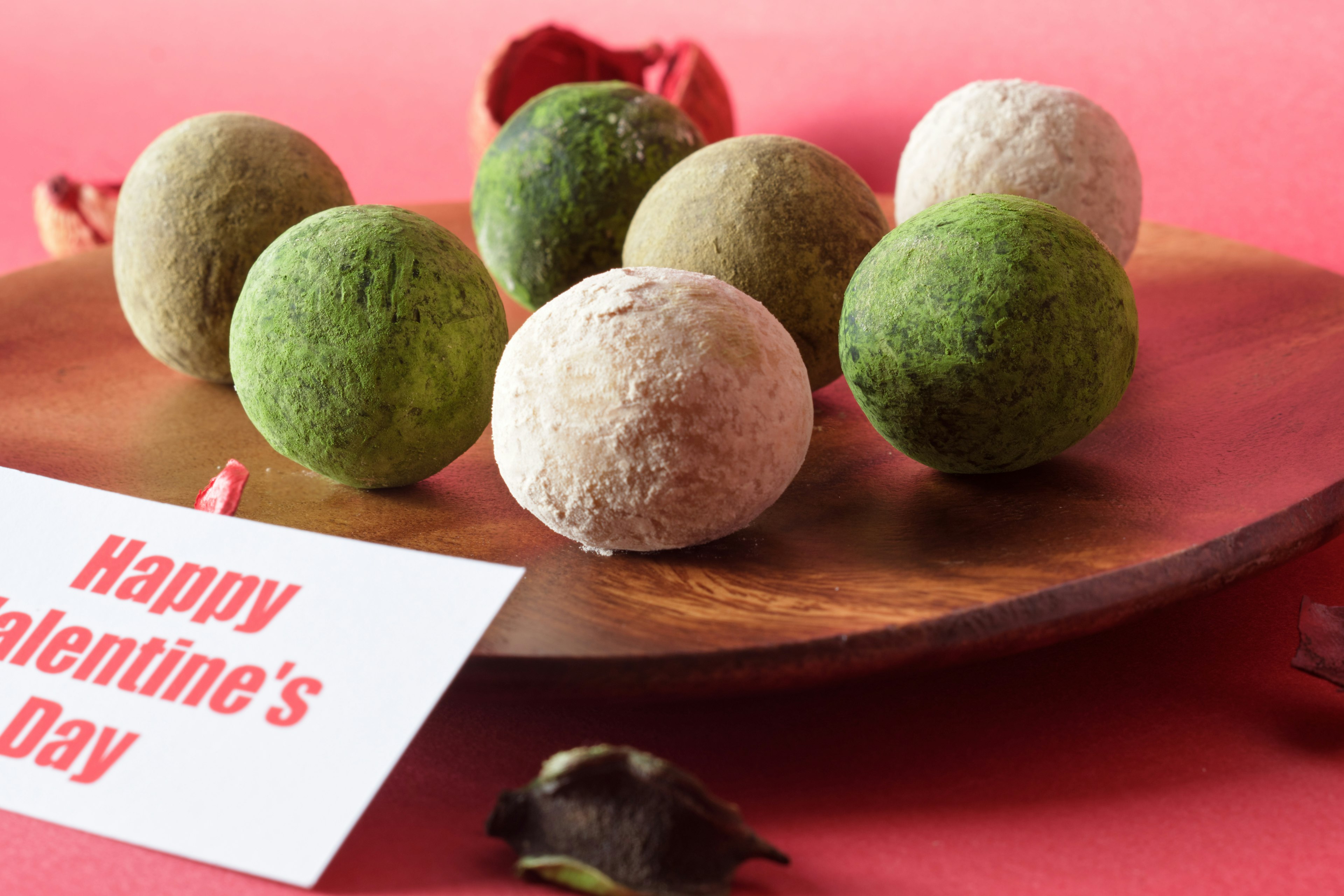 Boules colorées disposées sur une assiette en bois avec une carte Joyeuse Saint-Valentin