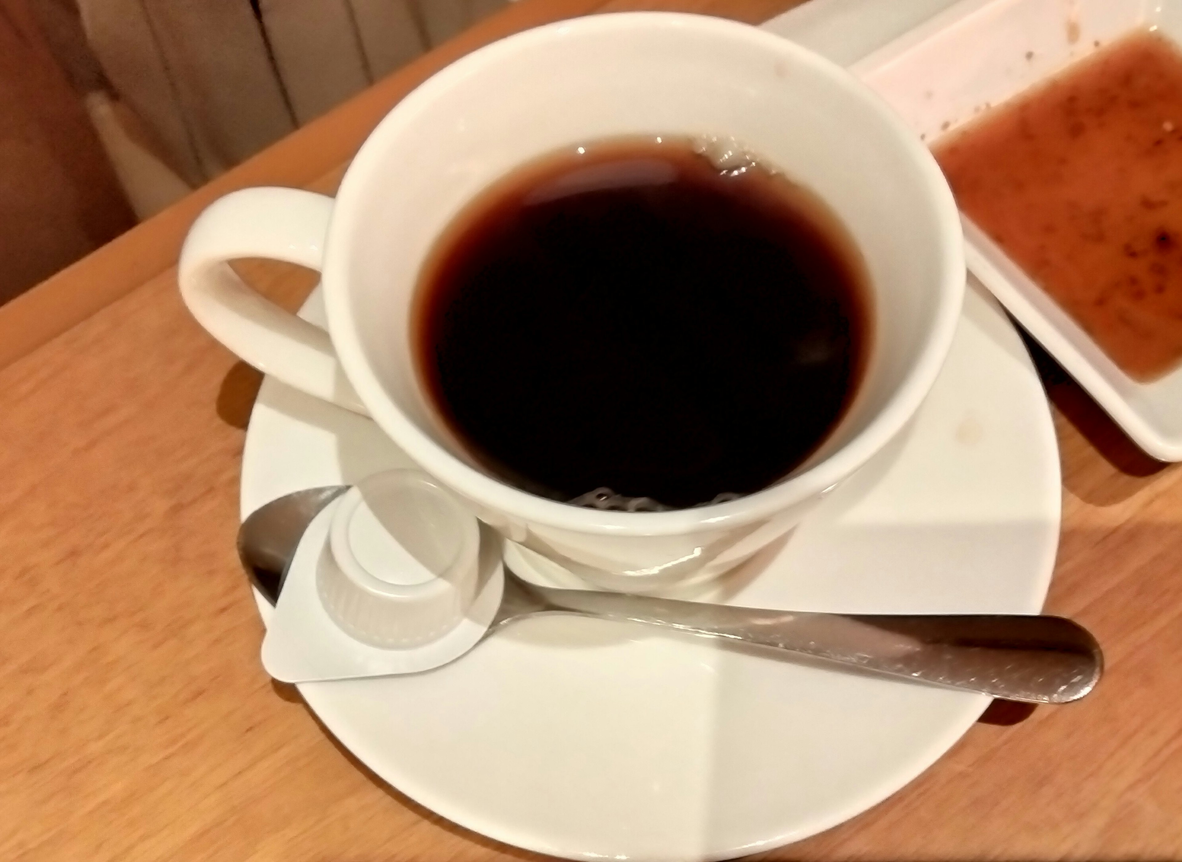 A white cup filled with black coffee and a spoon