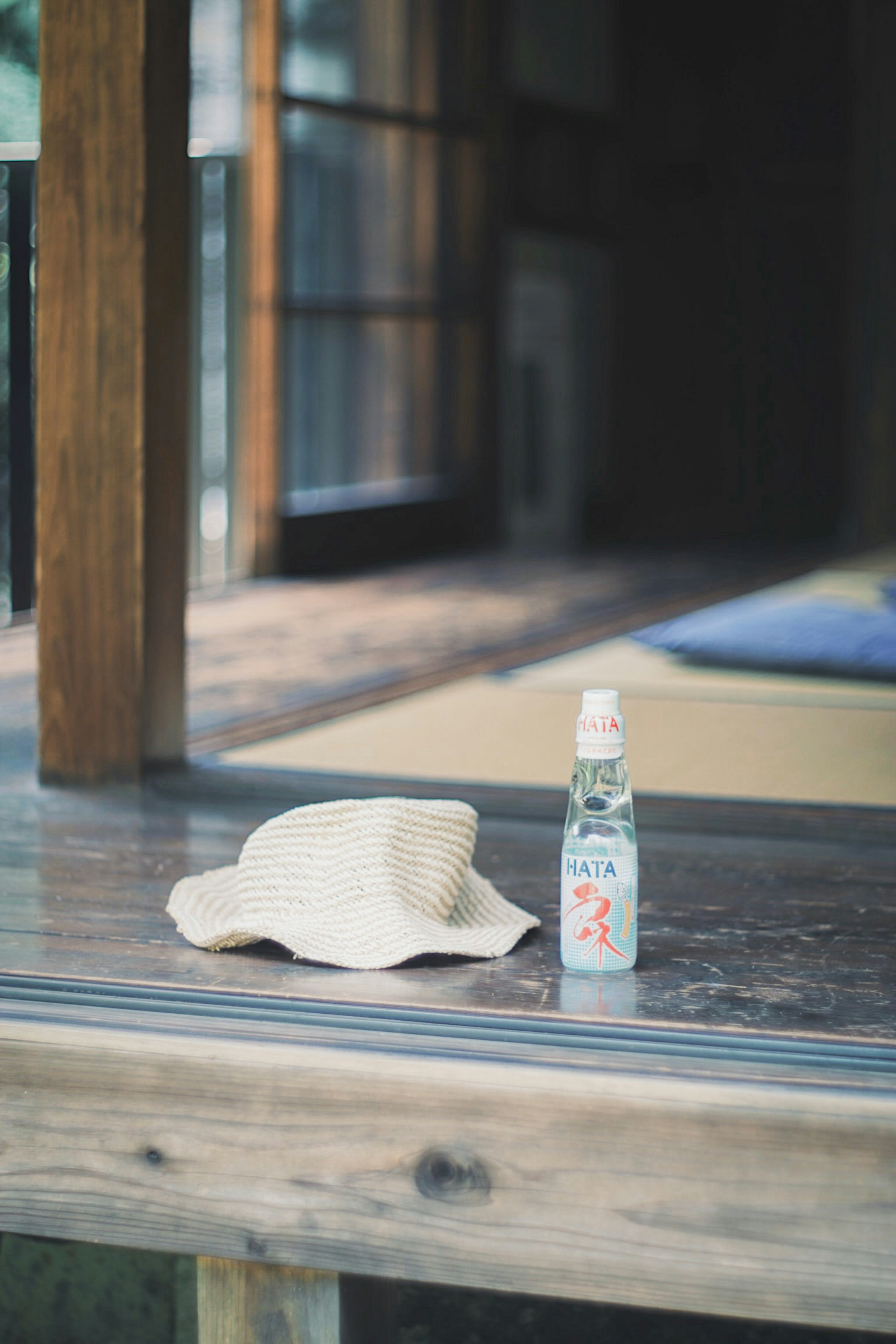 A straw hat and a bottle of soda on a wooden table