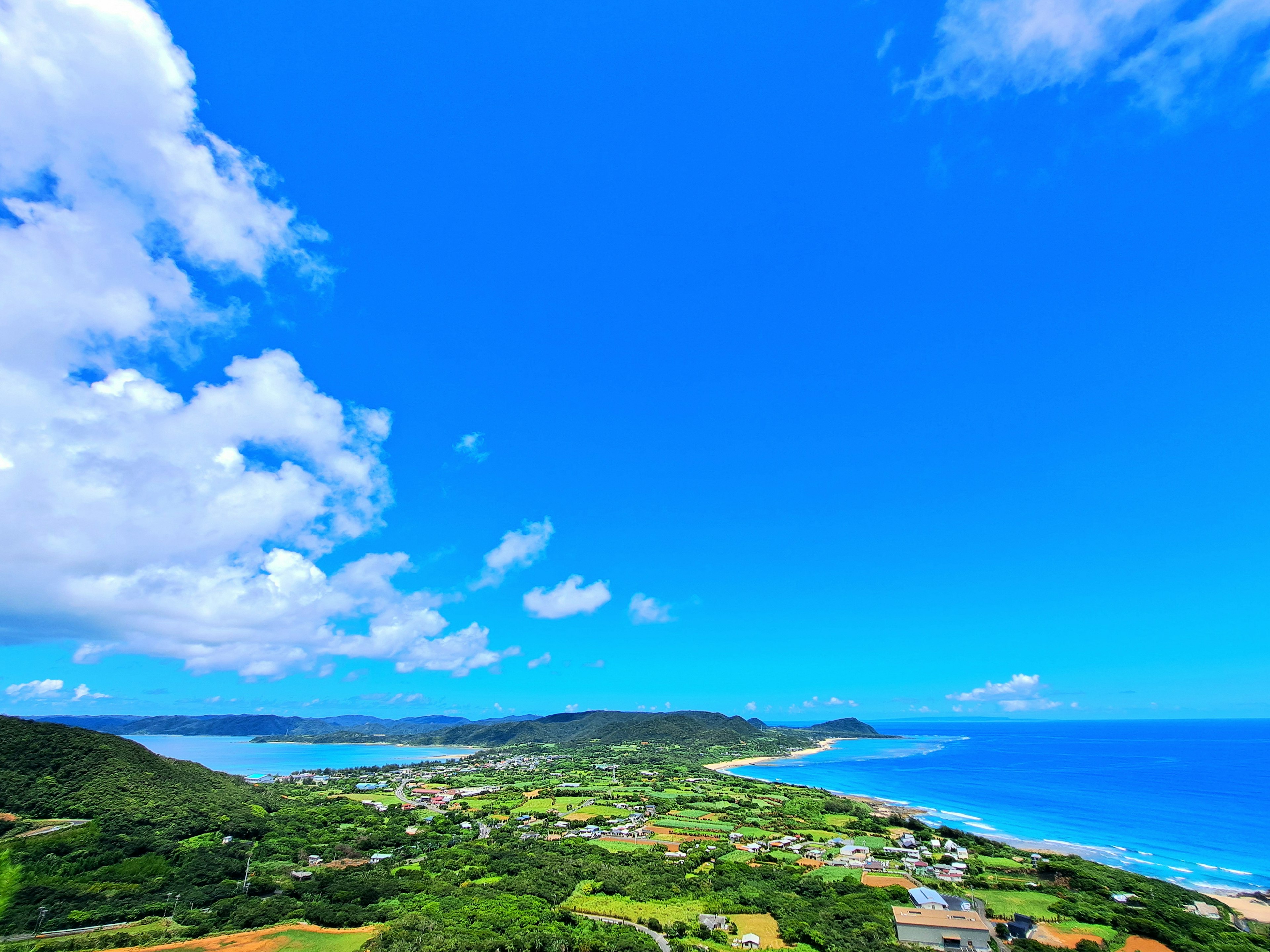 Panoramic view featuring a blue ocean and sky with lush green landscapes