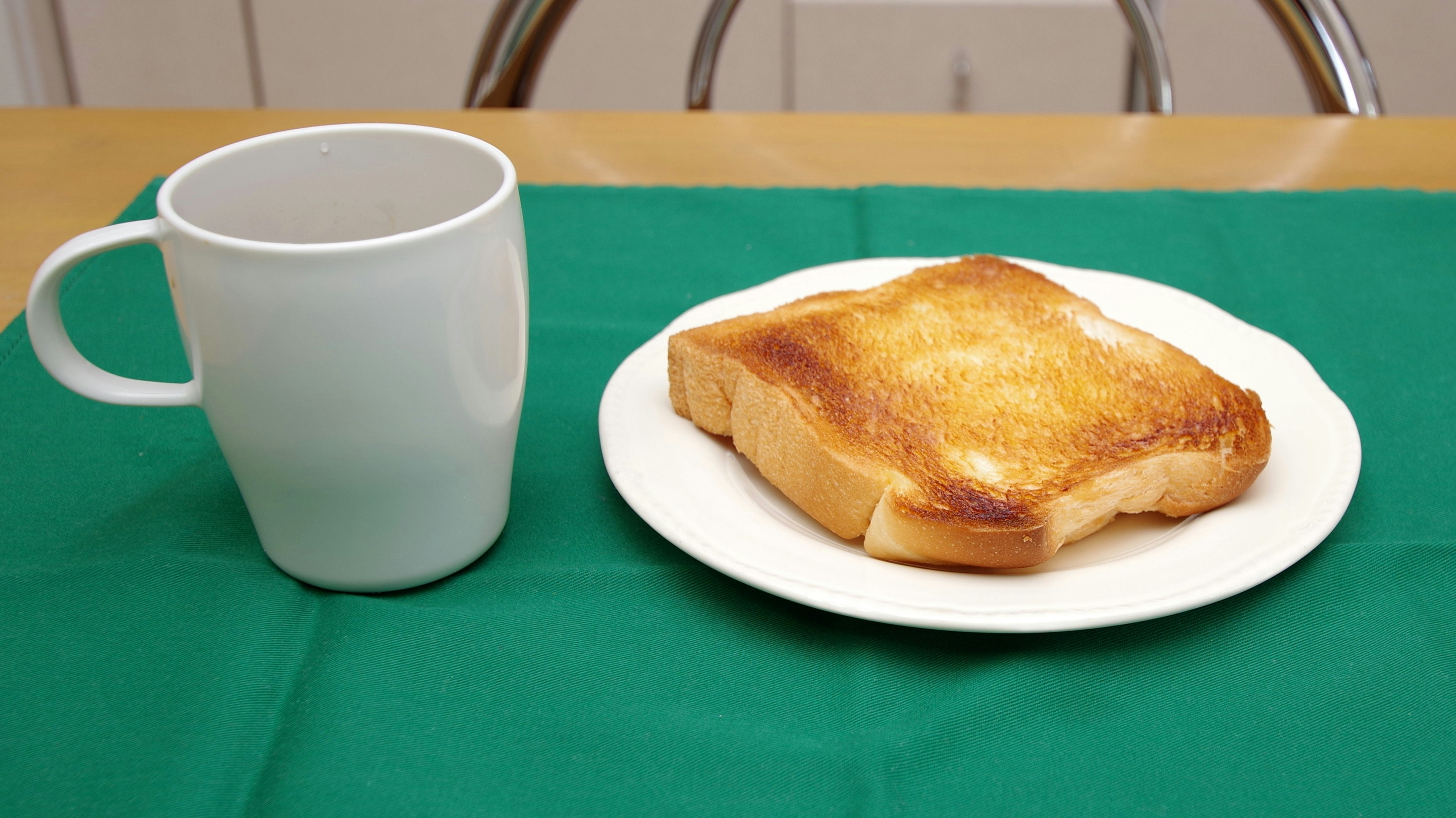 Tostada en un plato blanco junto a una taza azul claro sobre un mantel verde