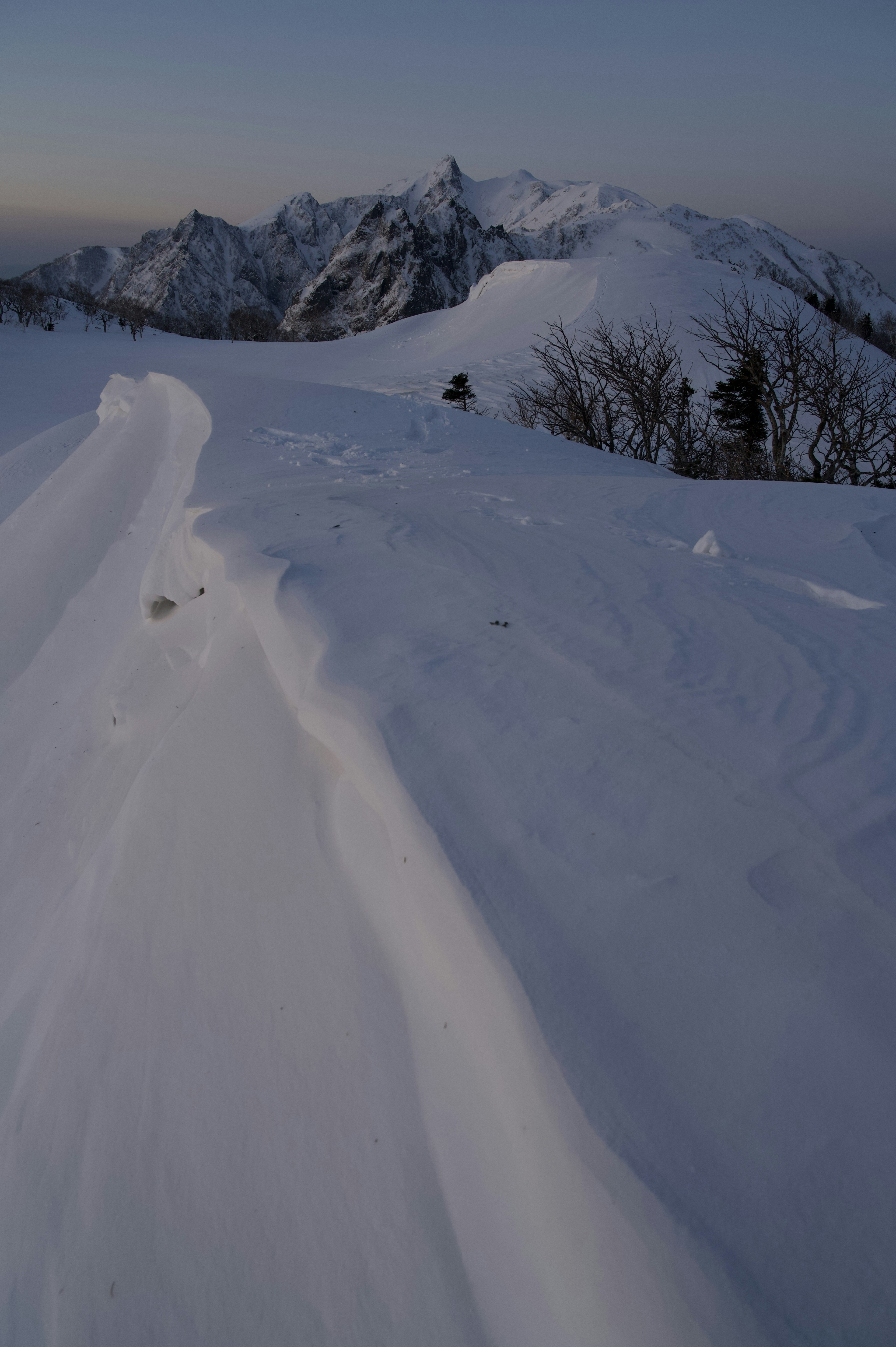 Montagne innevate con curve lisce di neve in primo piano