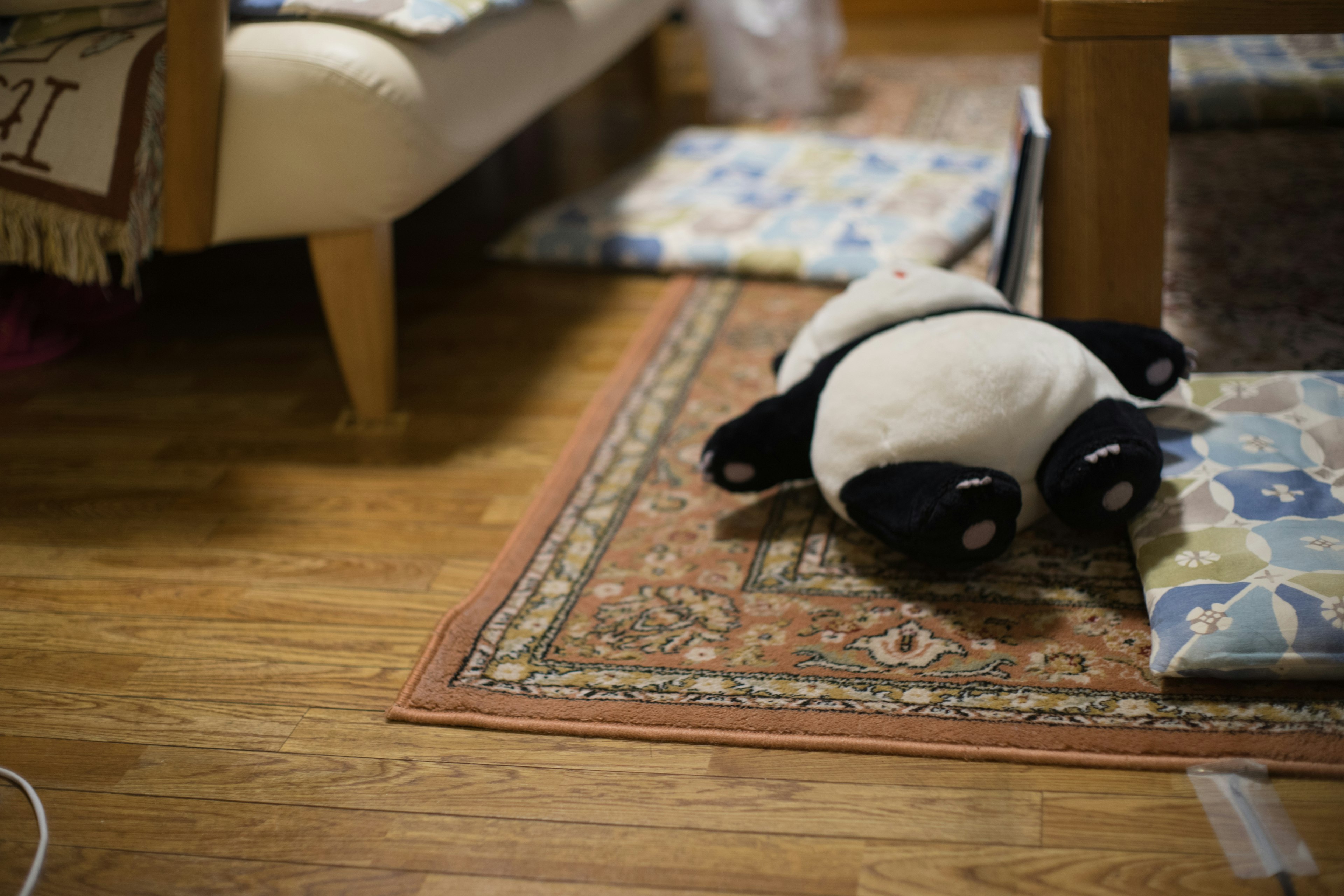 Un panda di peluche sdraiato su un tappeto decorato in un soggiorno