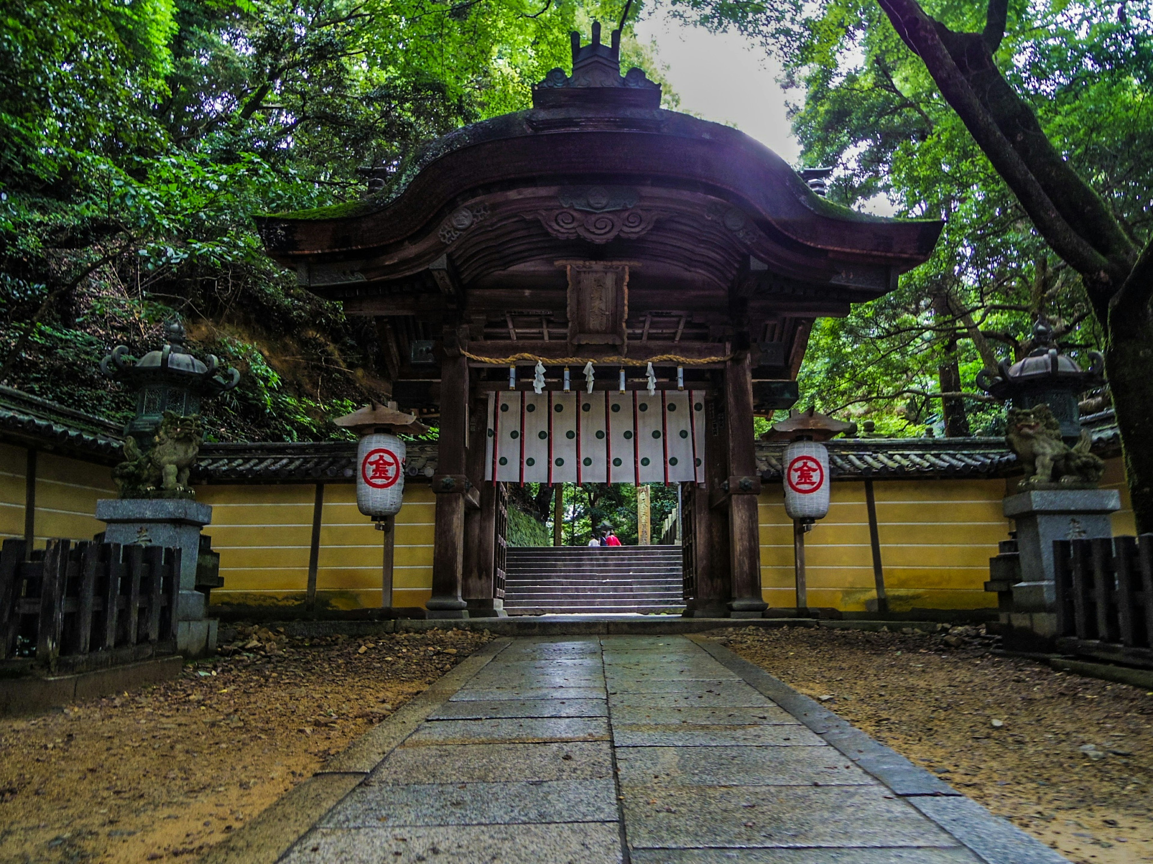 An ancient shrine gate surrounded by lush greenery in a tranquil setting