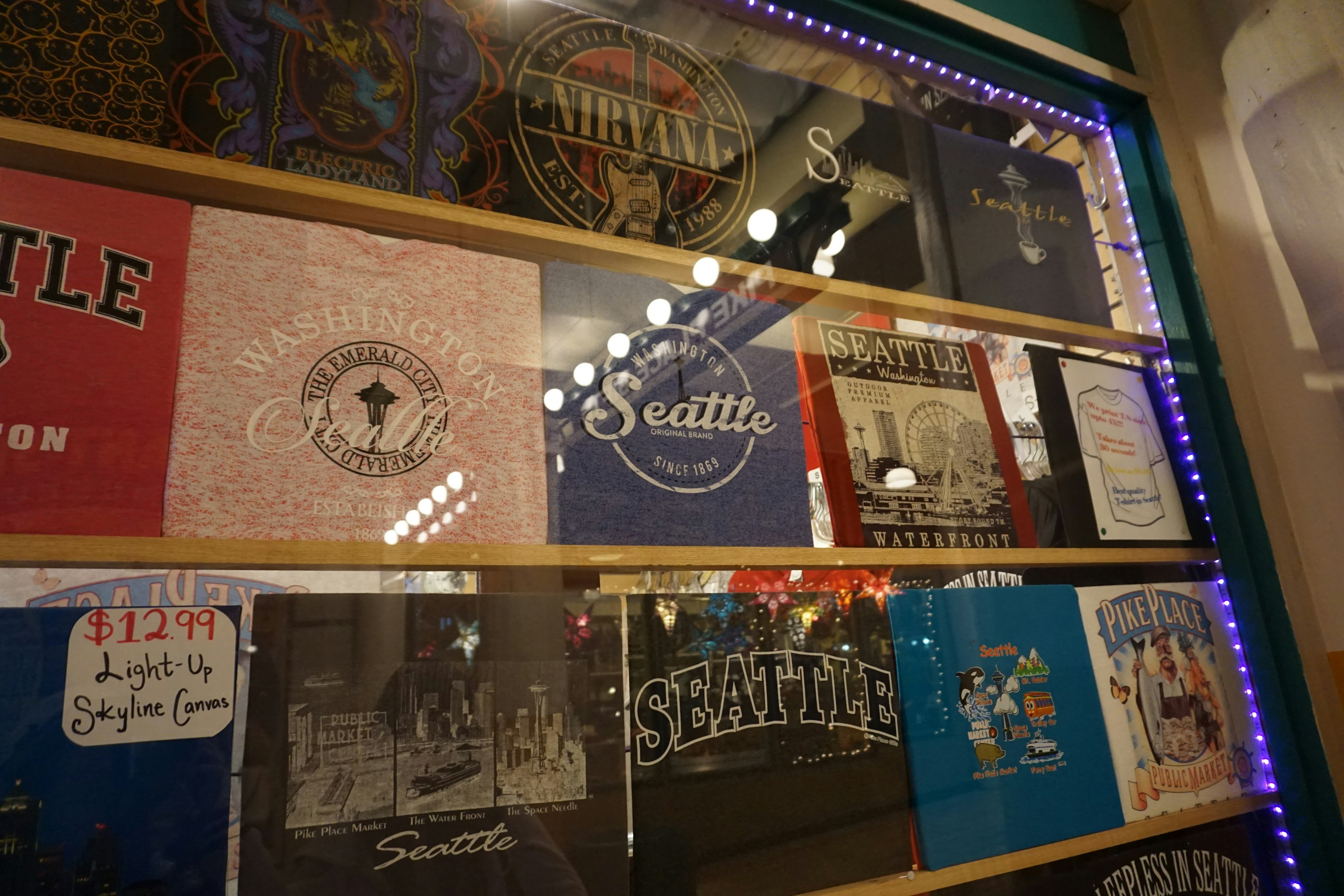 Display of various Seattle-themed T-shirts in a shop window