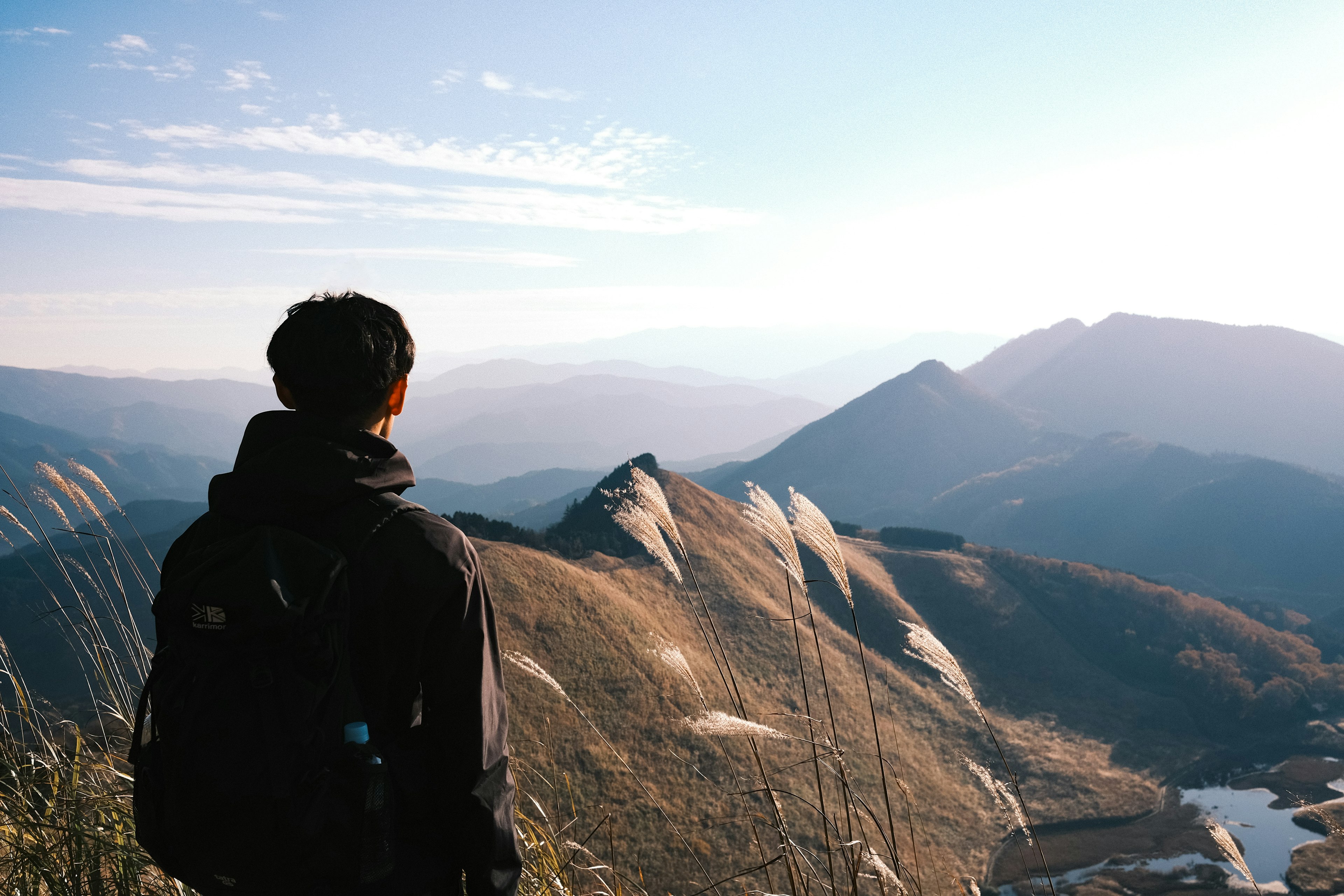 Person standing at mountain peak overlooking vast landscape