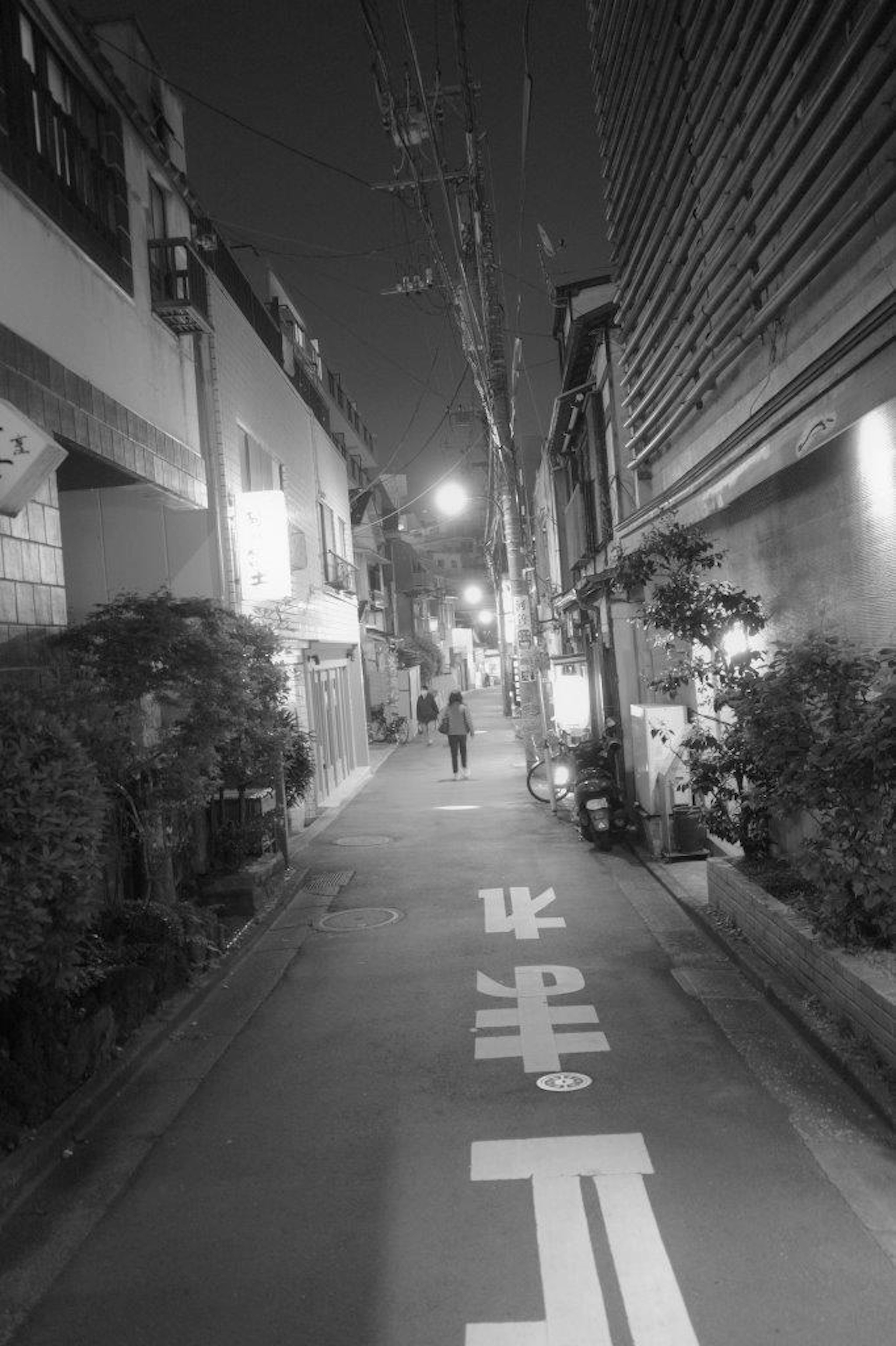 Une personne marchant dans une ruelle tranquille la nuit avec des bâtiments environnants