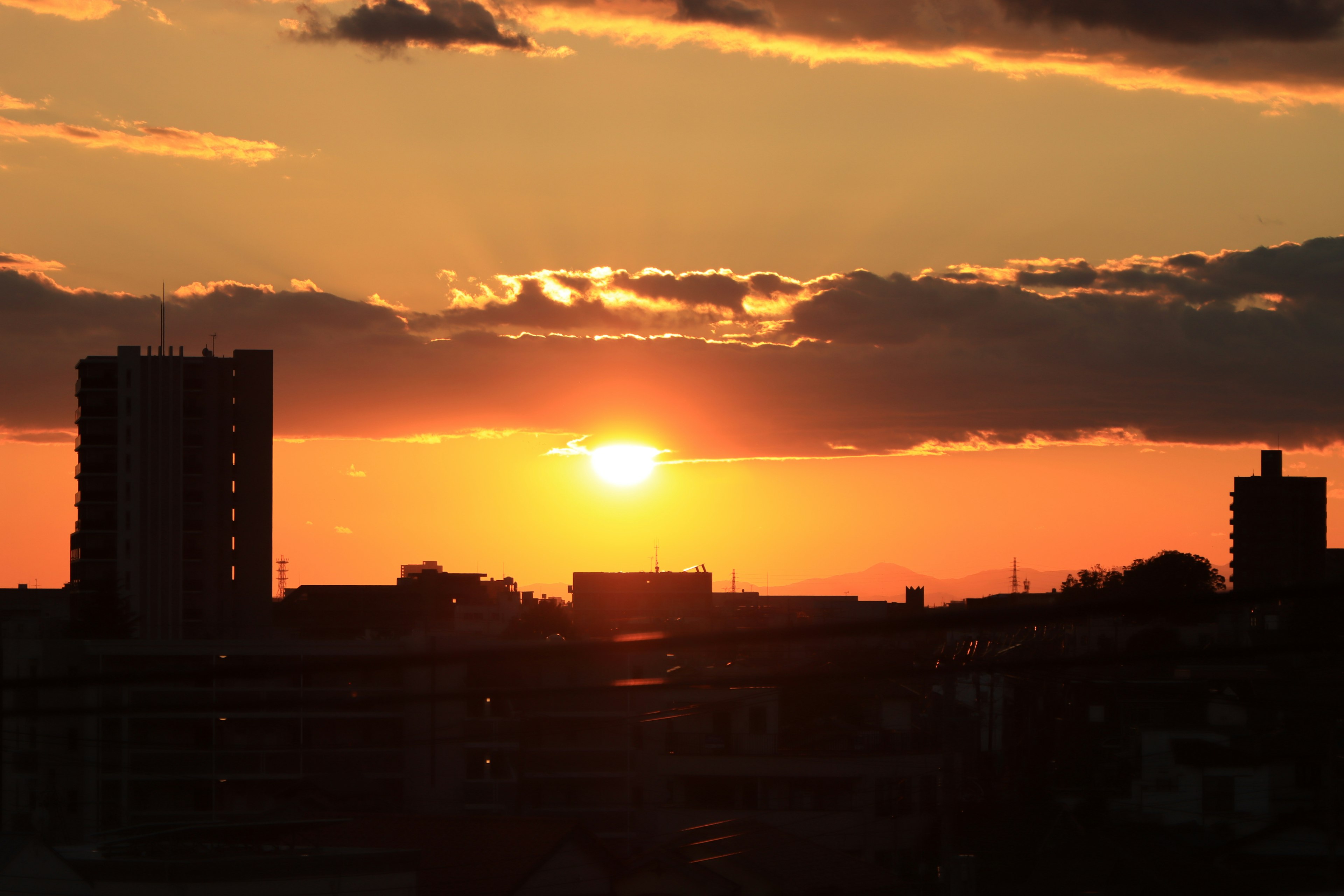 Silhouette d'une ville au coucher du soleil avec un ciel orange et jaune