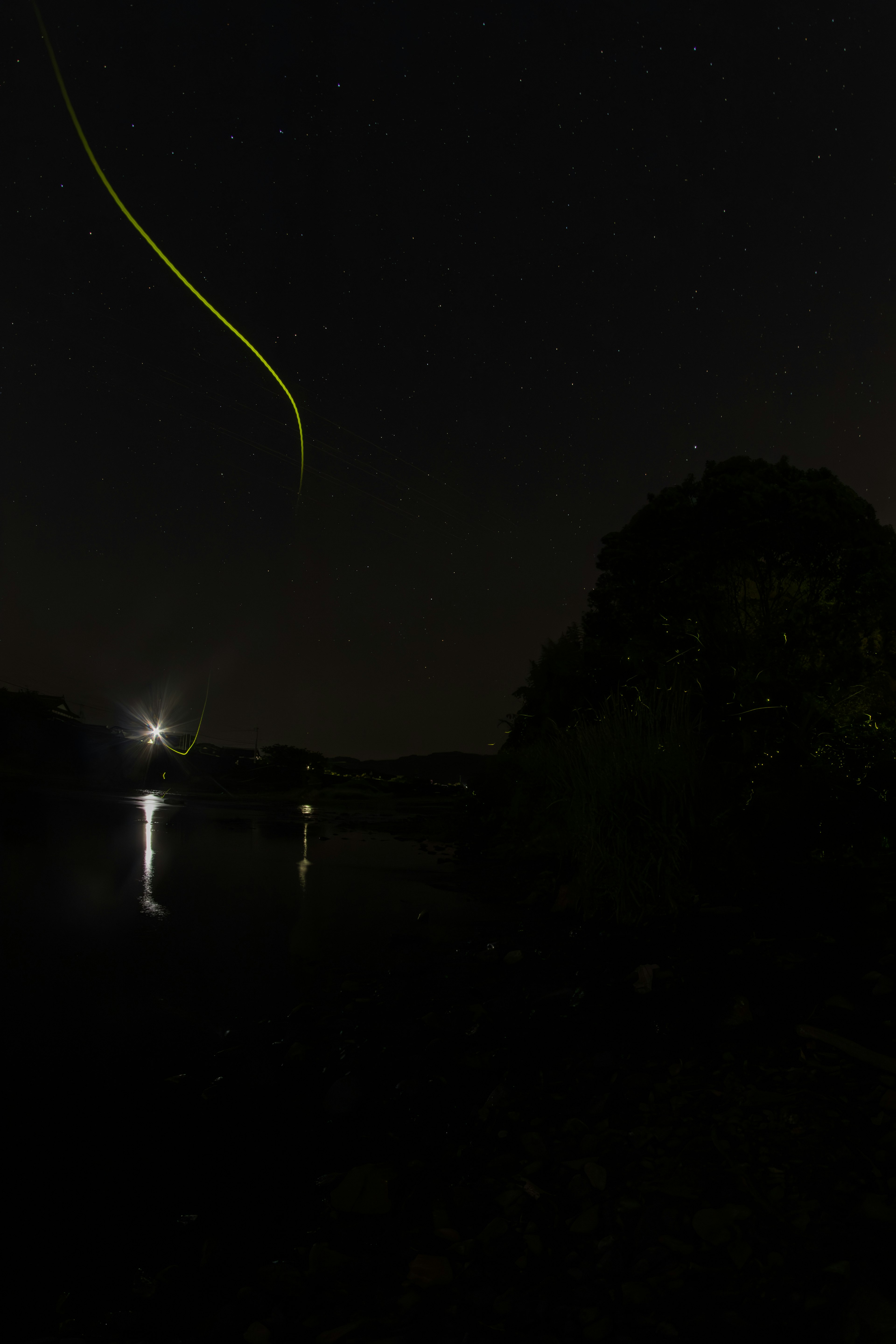 A dark sky with stars and a green light trail visible