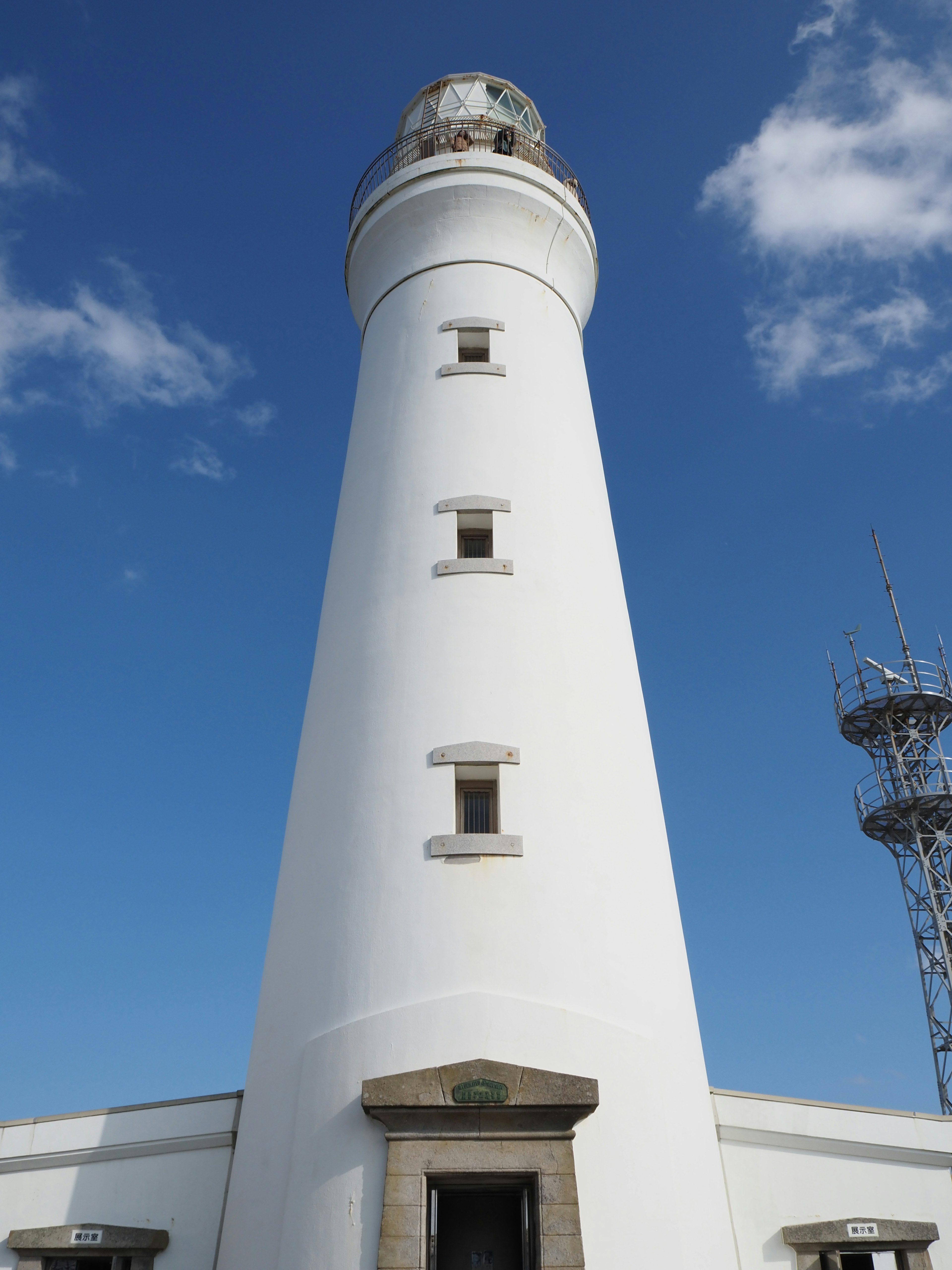 A white lighthouse standing under a blue sky