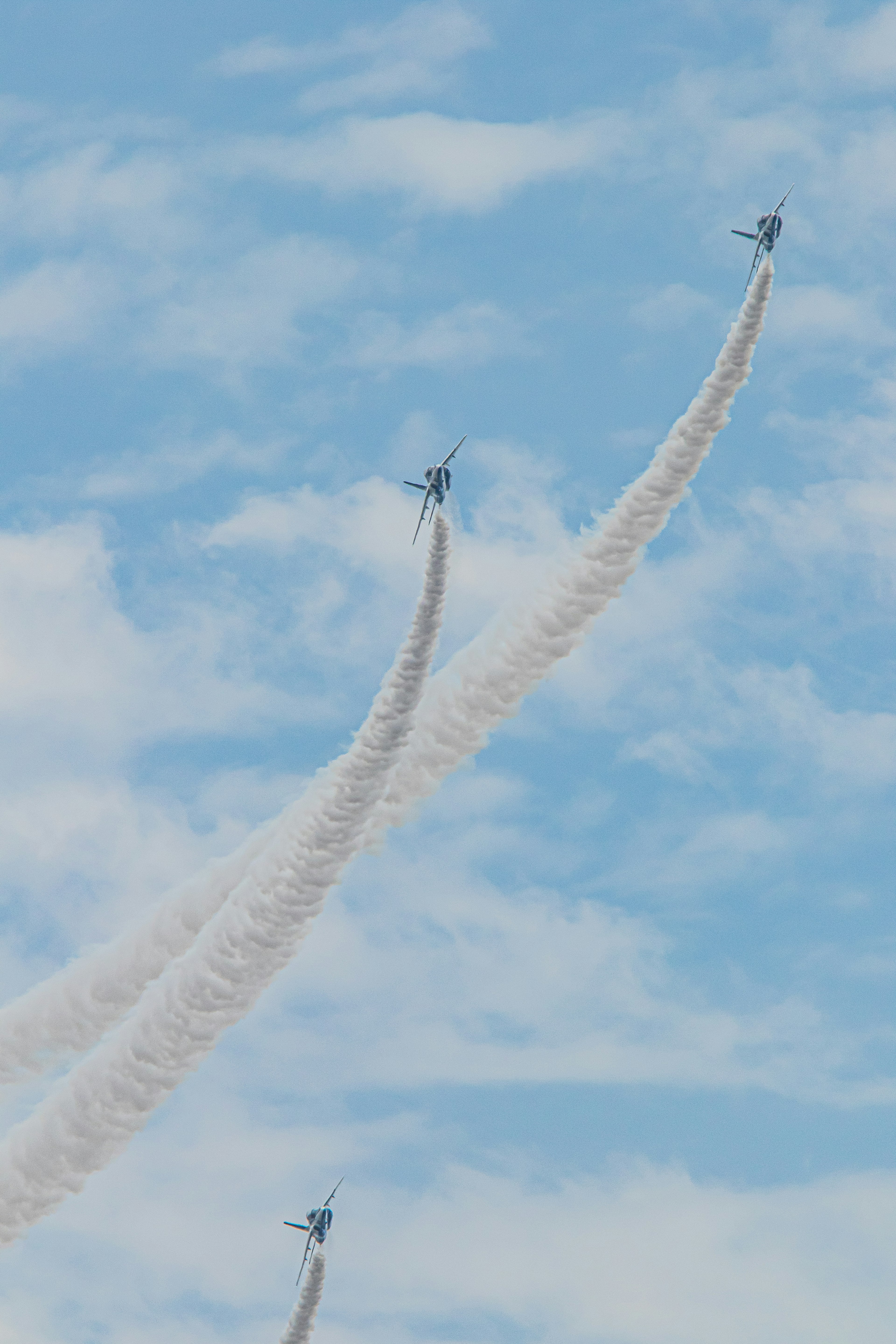 Flugzeuge, die im Himmel mit weißen Rauchspuren vor blauem Hintergrund fliegen