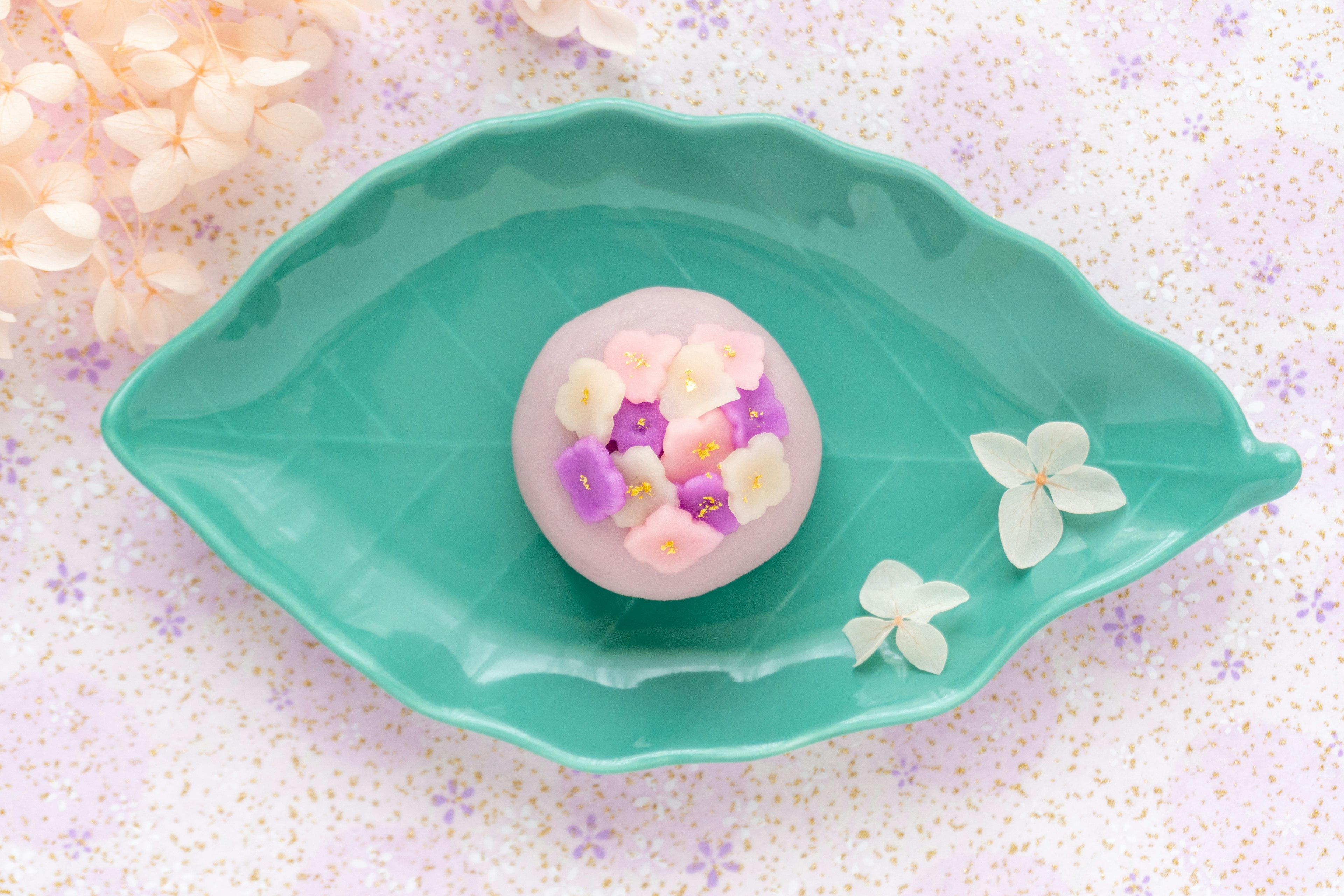 Colorful Japanese sweets placed on a green leaf-shaped plate with small flowers