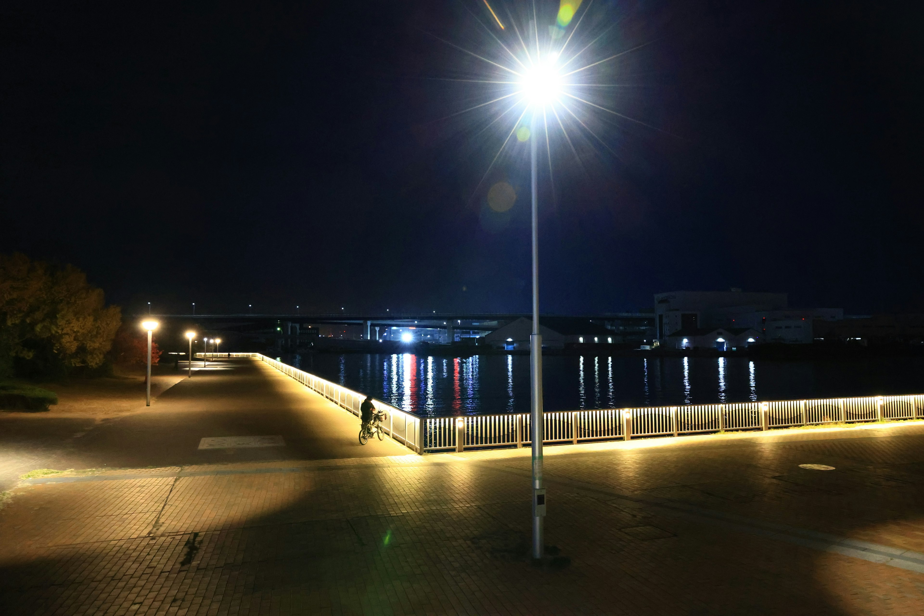 Night view of a riverside promenade with bright streetlights