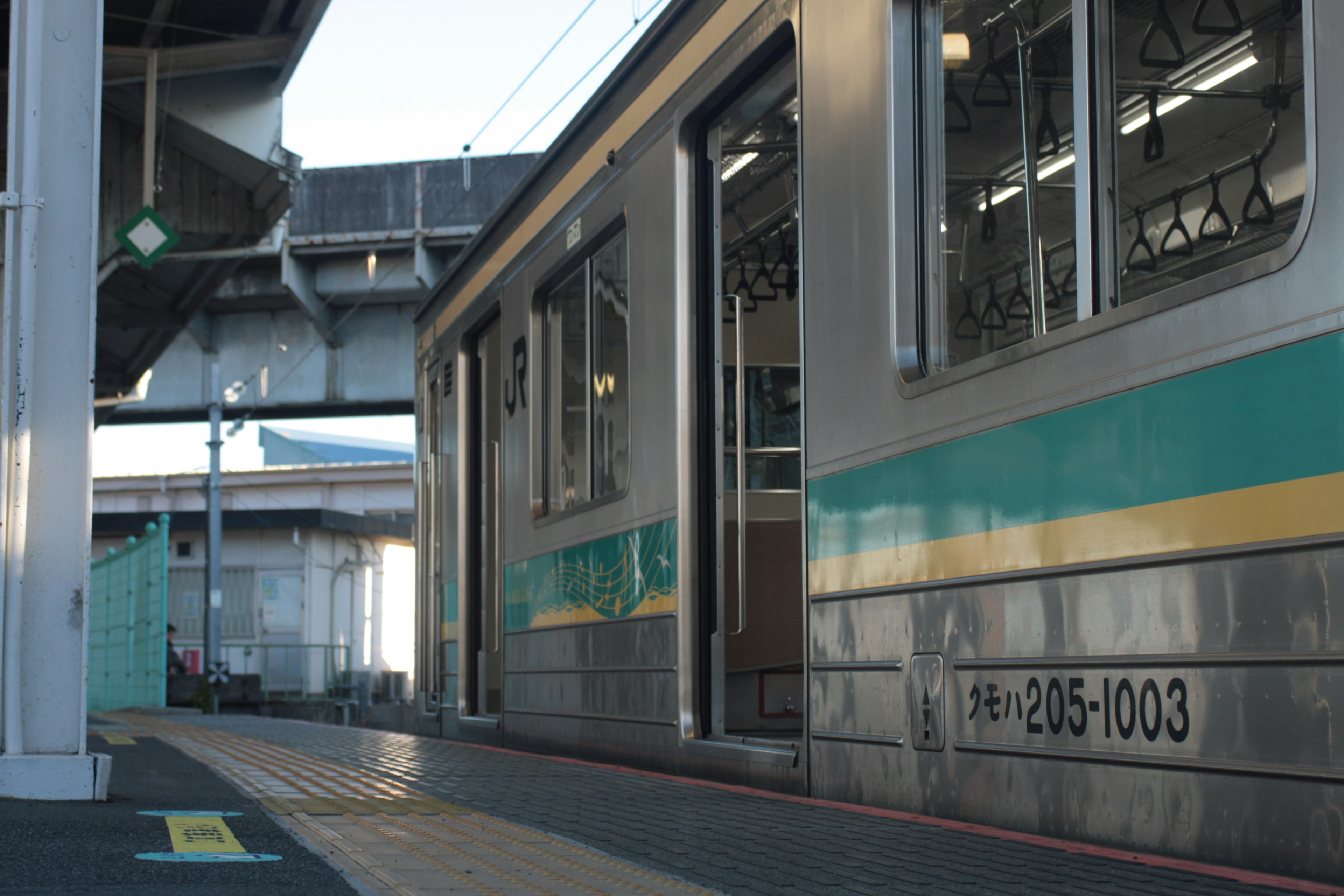 駅のプラットフォームに停車中の電車の側面とドアが見える