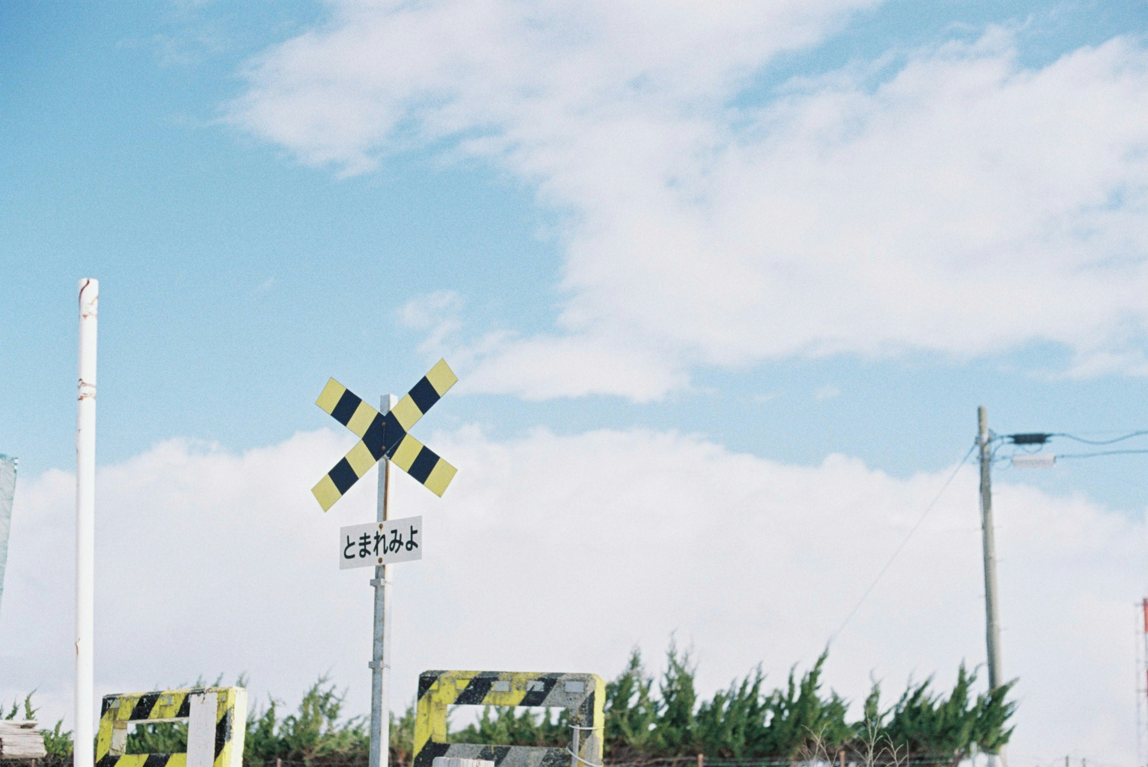 Railroad crossing signal under a blue sky with white clouds