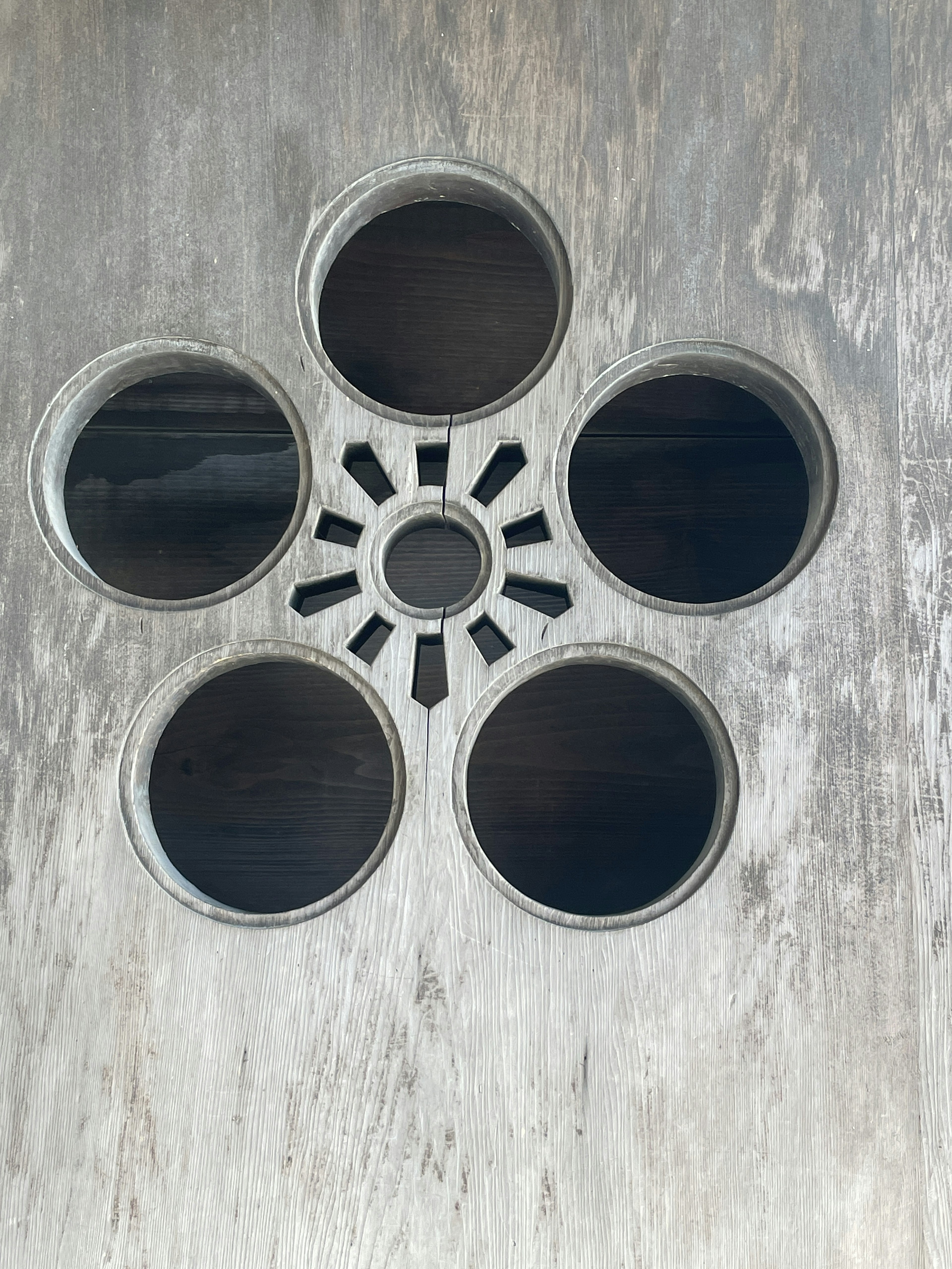 Panel metálico con cinco agujeros circulares dispuestos en un patrón de flor y un agujero central más pequeño